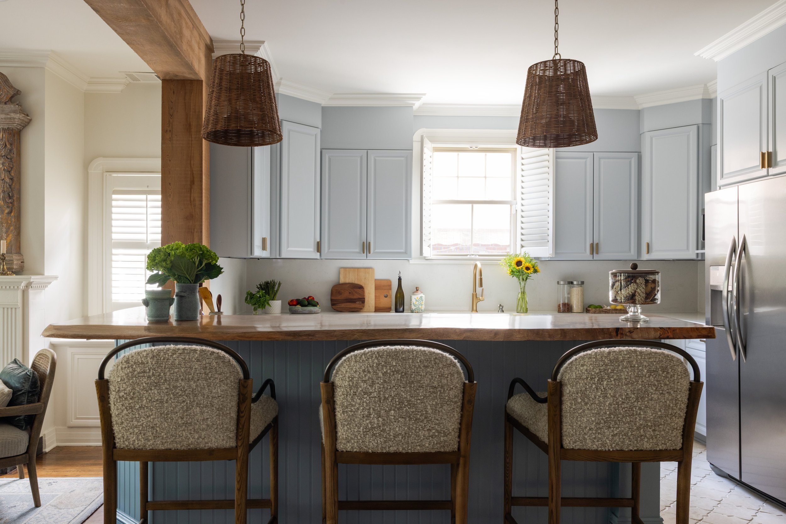 Blue kitchen with cabinets to the ceiling, live-edge wood counter, and boucle stools