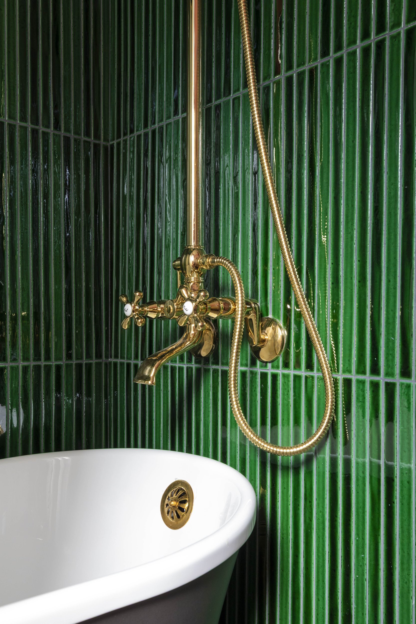 Brass tub filler and handheld shower on green tile