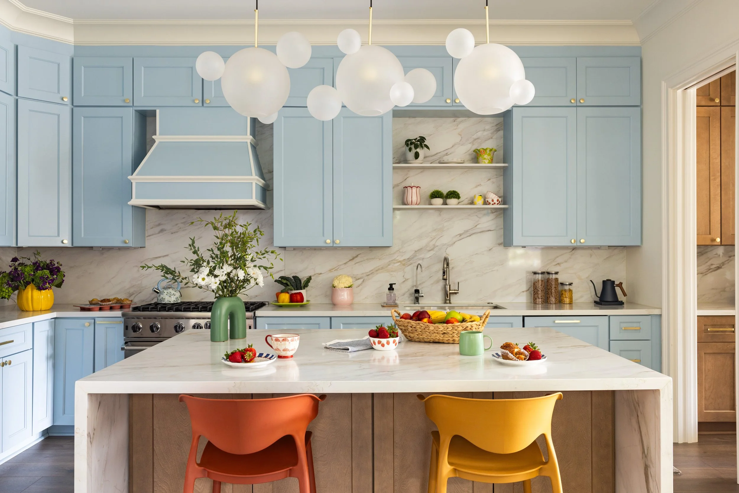 Light blue kitchen with bubble glass pendants and marble waterfall island