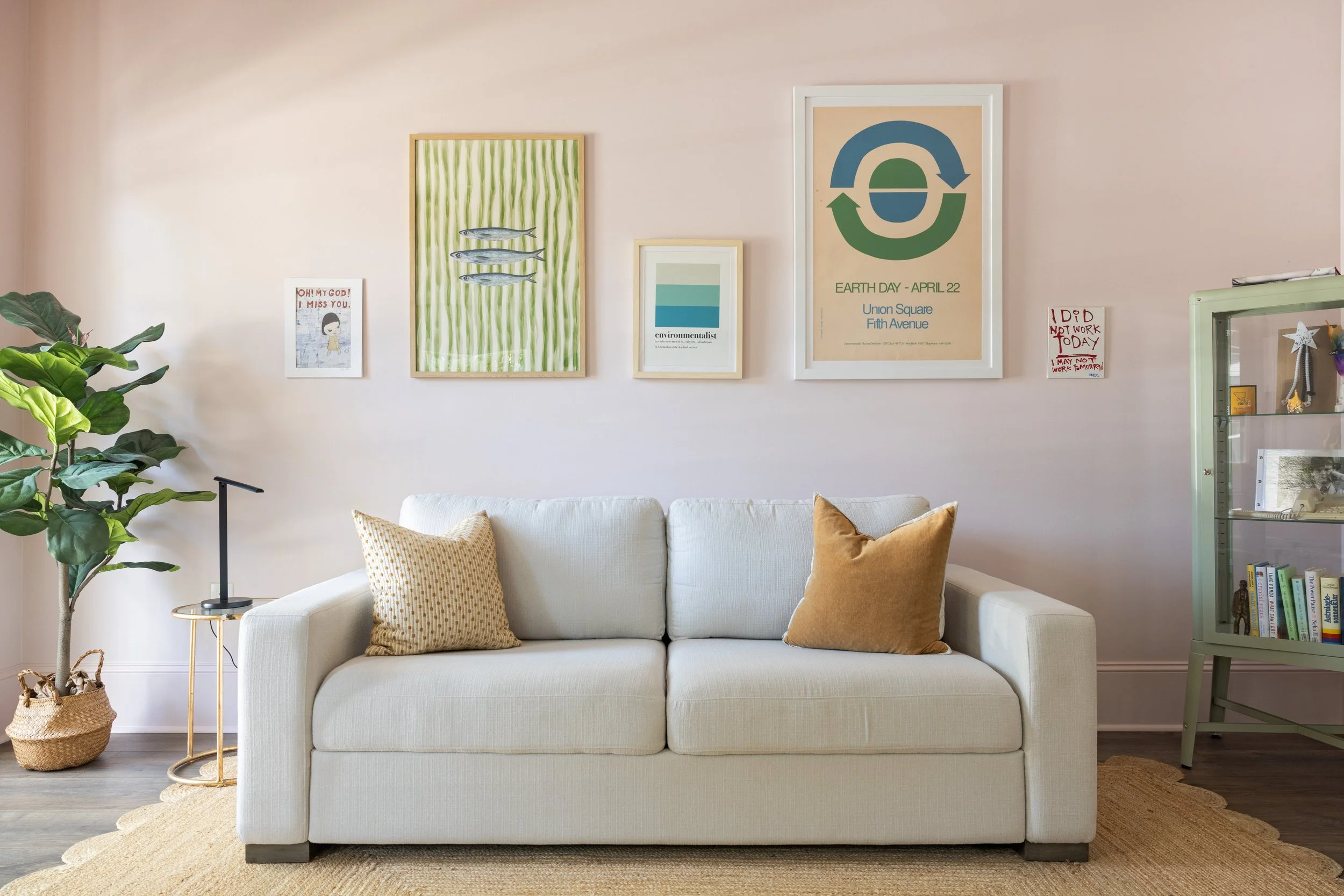 Pink room with linen sofa, gallery wall, and green glass cabinet