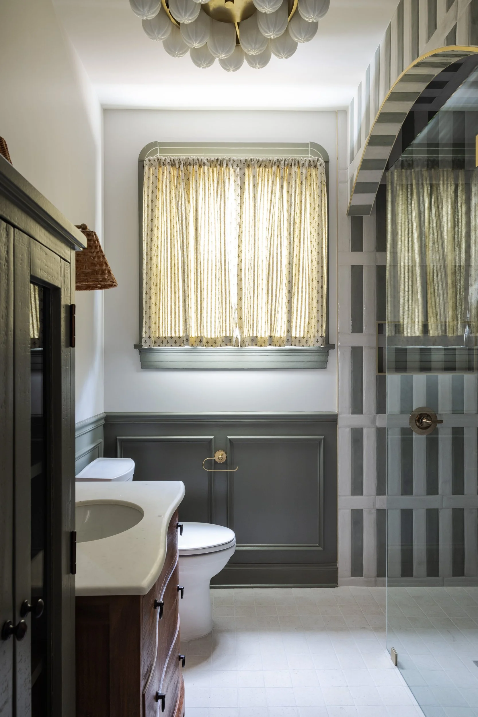 Bathroom with a green striped tile arch over the shower and green paneled walls