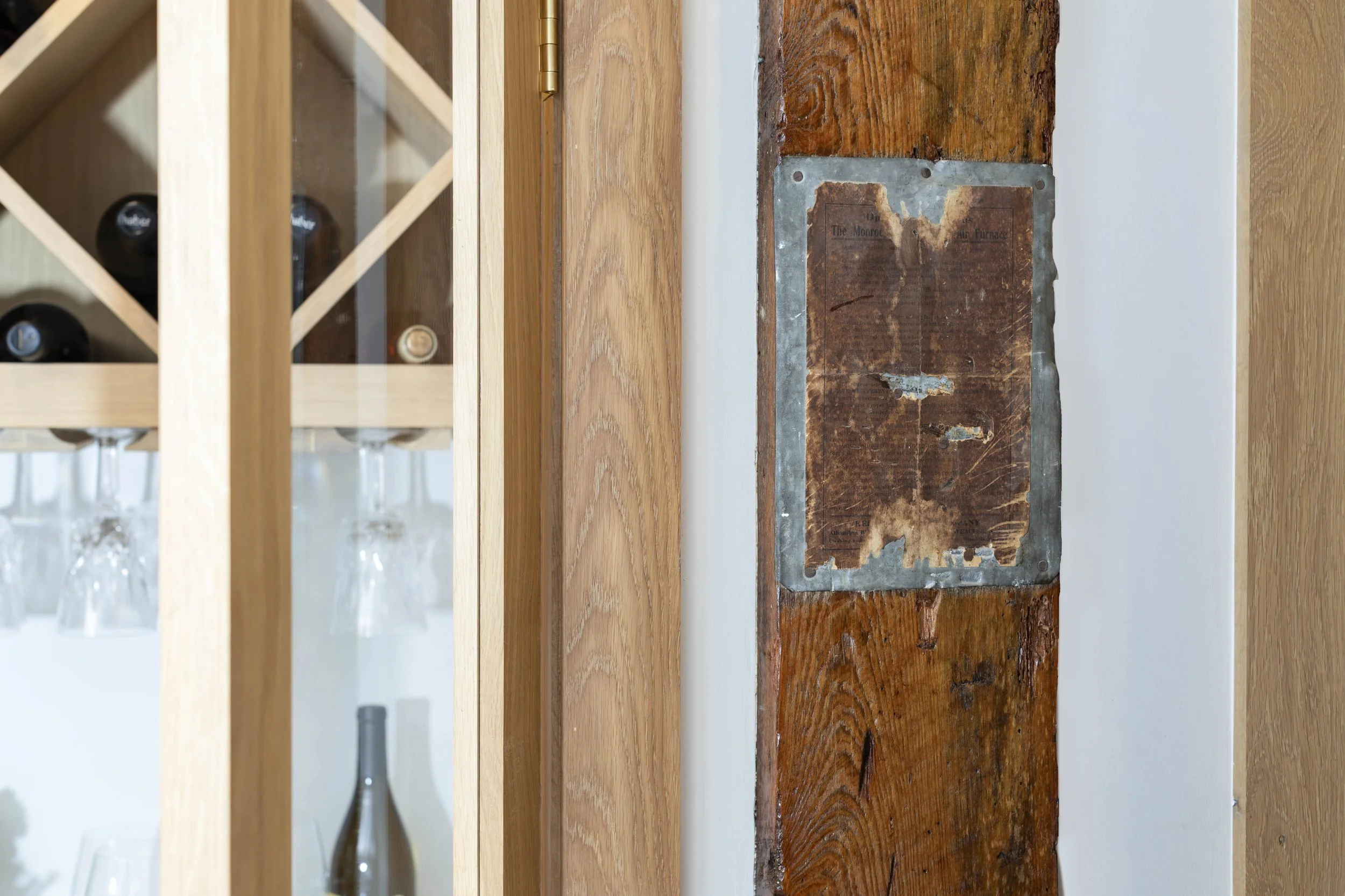 Wine closet beside timber post with antique furnace instruction plate