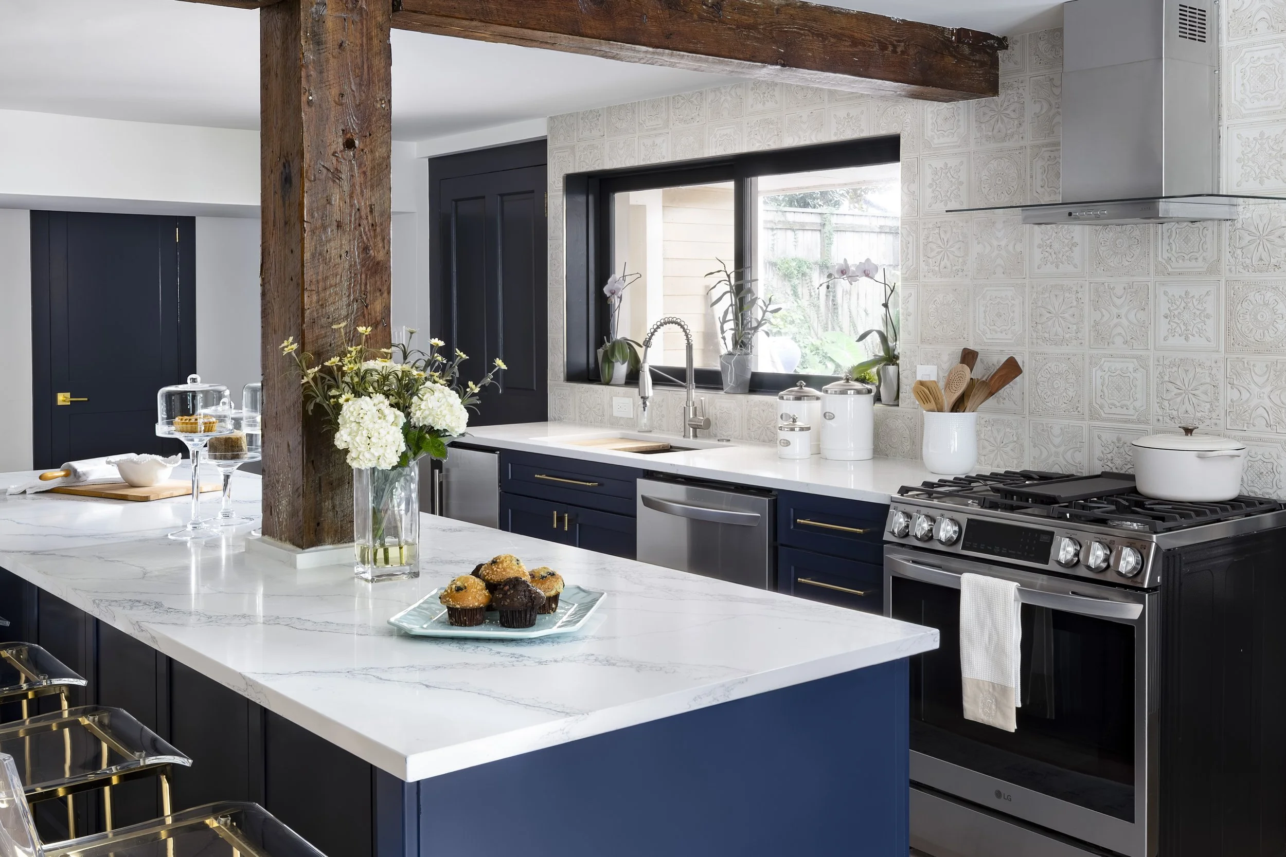 Kitchen island with pass-through pool window in New Orleans home by Val Spaces
