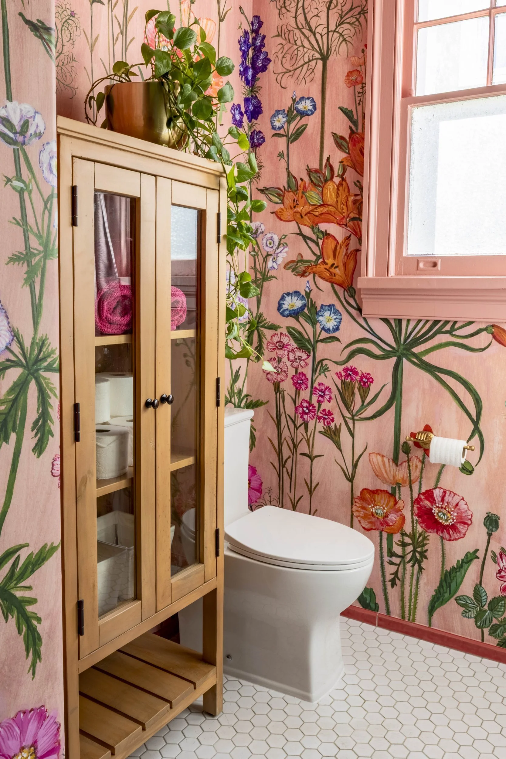 Vintage wood and glass cabinet against floral wallpaper