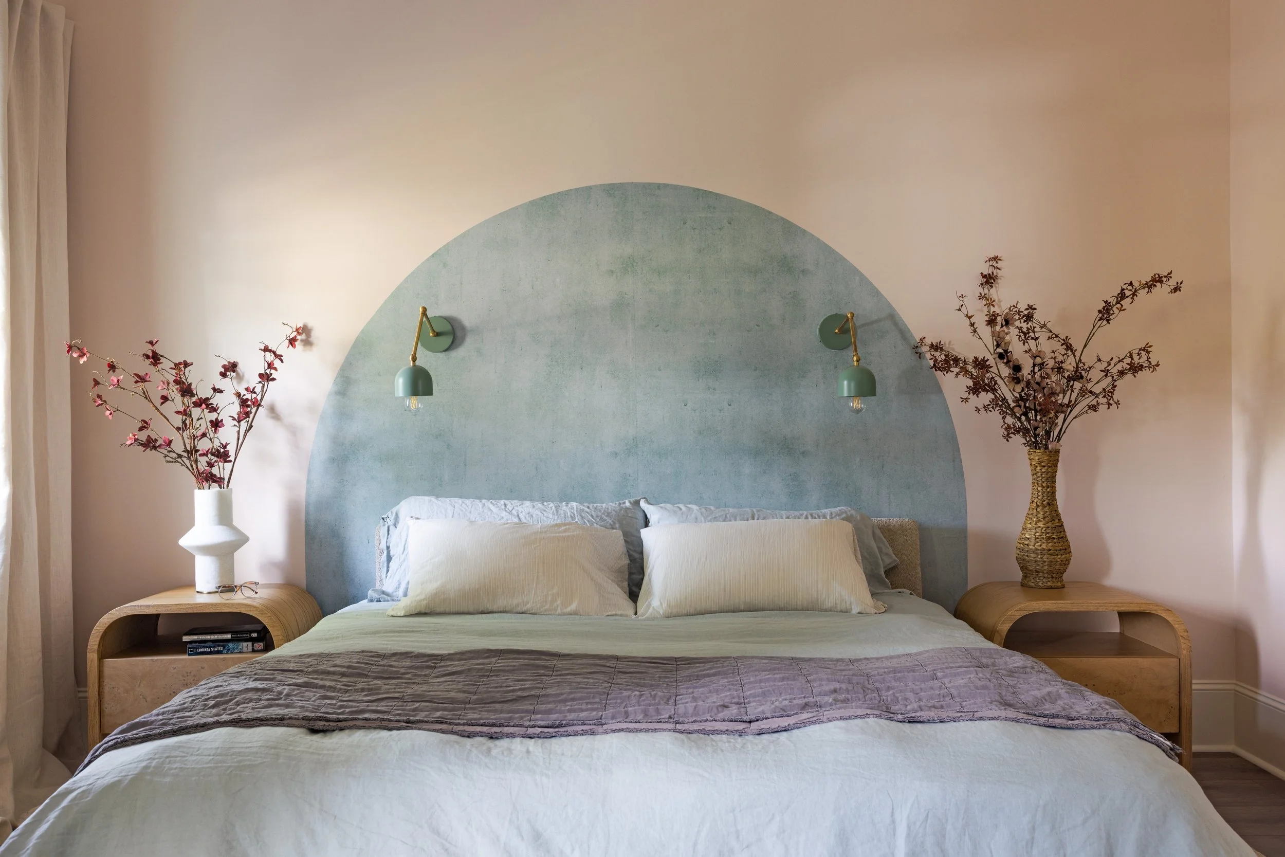 Primary bedroom with painted arch headboard wall and green sconces