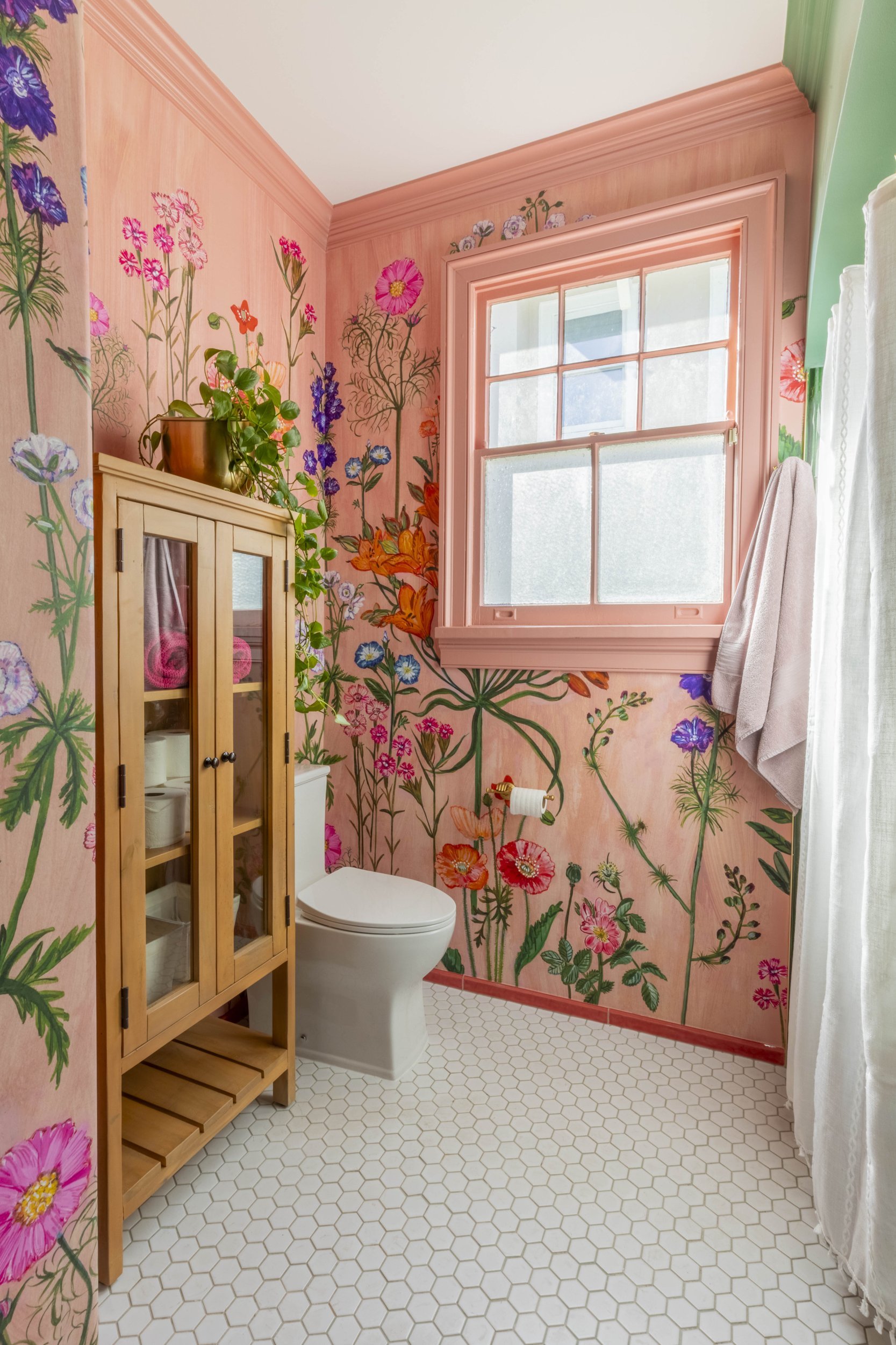 Bathroom with Lucy Tiffney hand-drawn pink floral wallpaper and white hex tile floor in a Lakeview New Orleans home