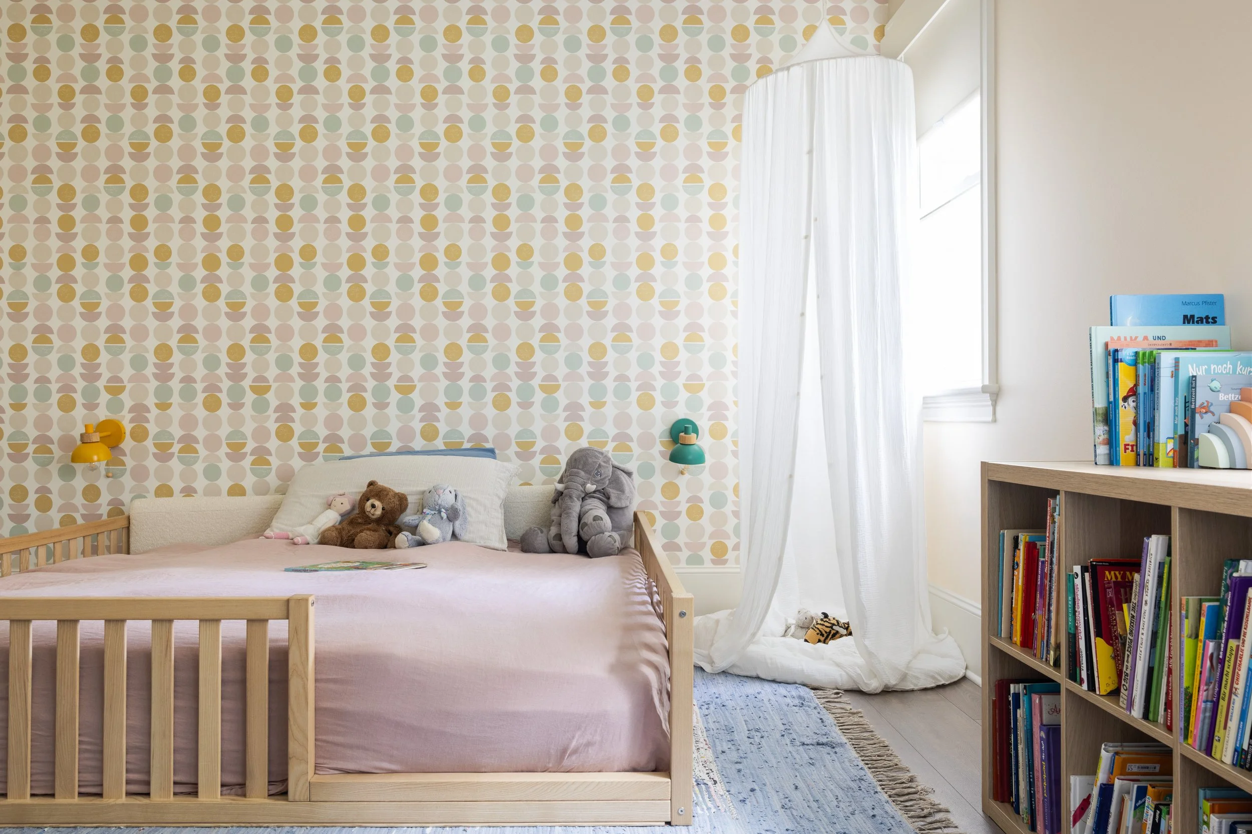 Child's bedroom with geometric wallpaper, floor bed, and reading canopy