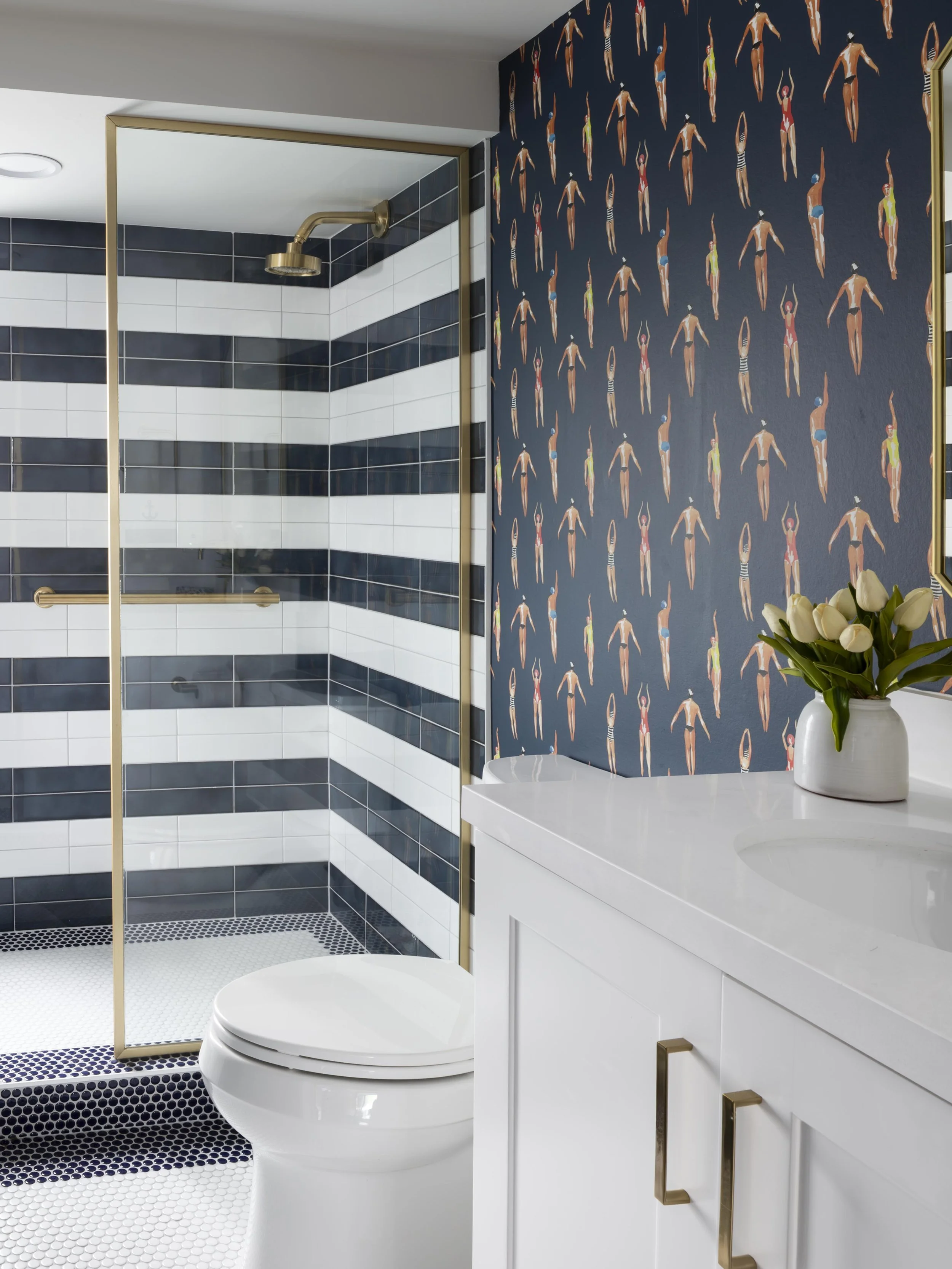 Pool bathroom with swimmer wallpaper and striped tile in New Orleans by Val Spaces