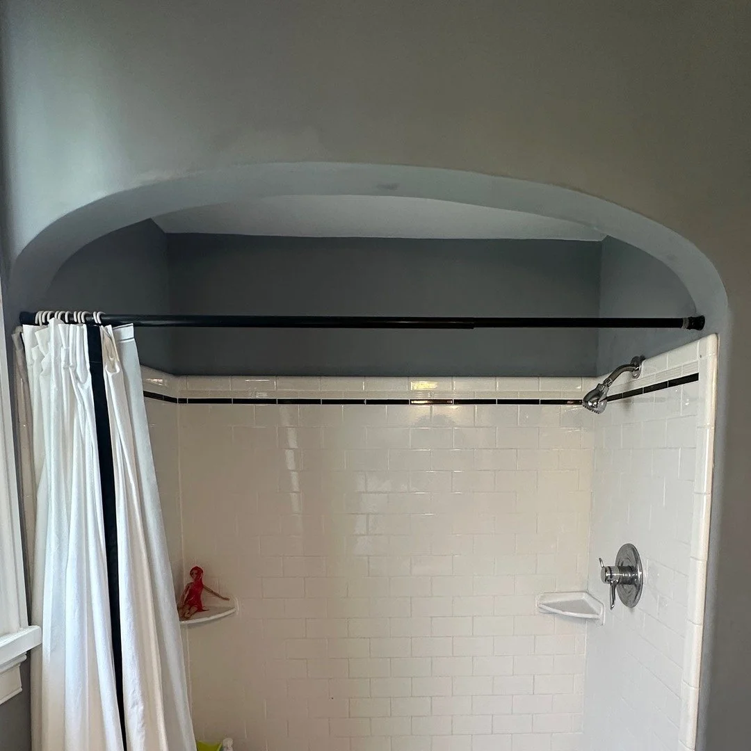 Before: the arched alcove with a curtained shower and white subway tile