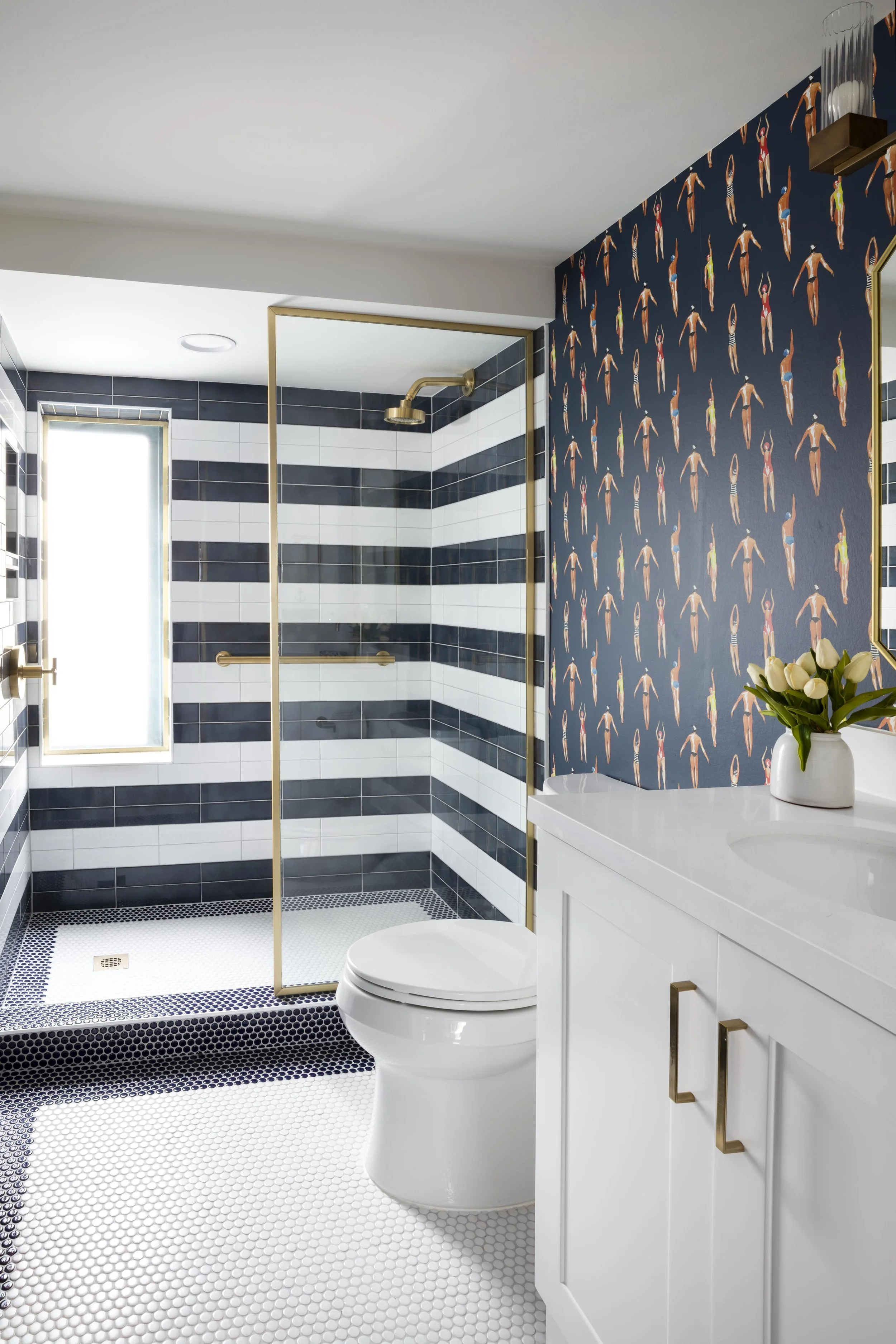 Pool bathroom with swimmer wallpaper and navy striped shower