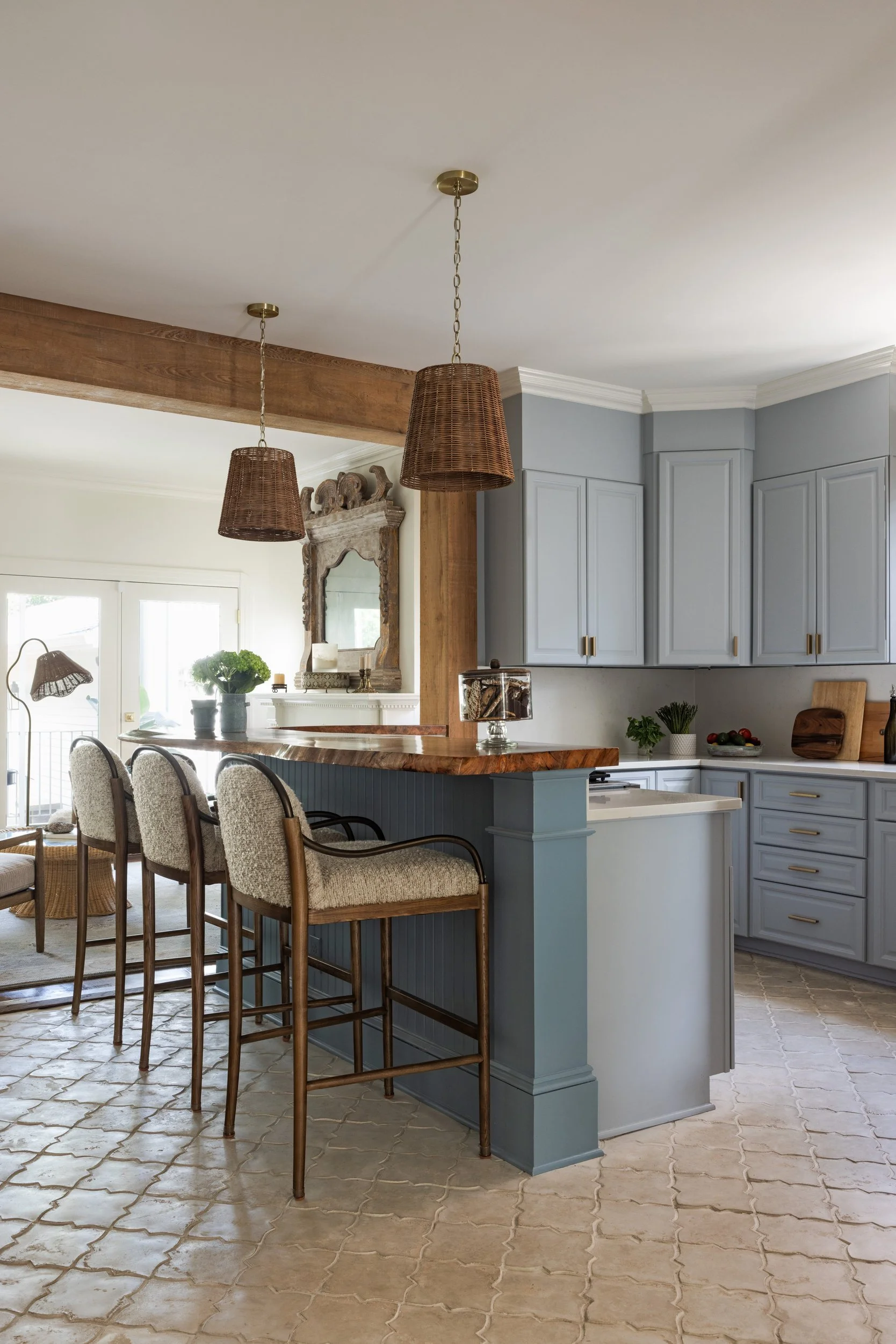 Blue-gray kitchen cabinets with brass pulls and cream arabesque floor tile