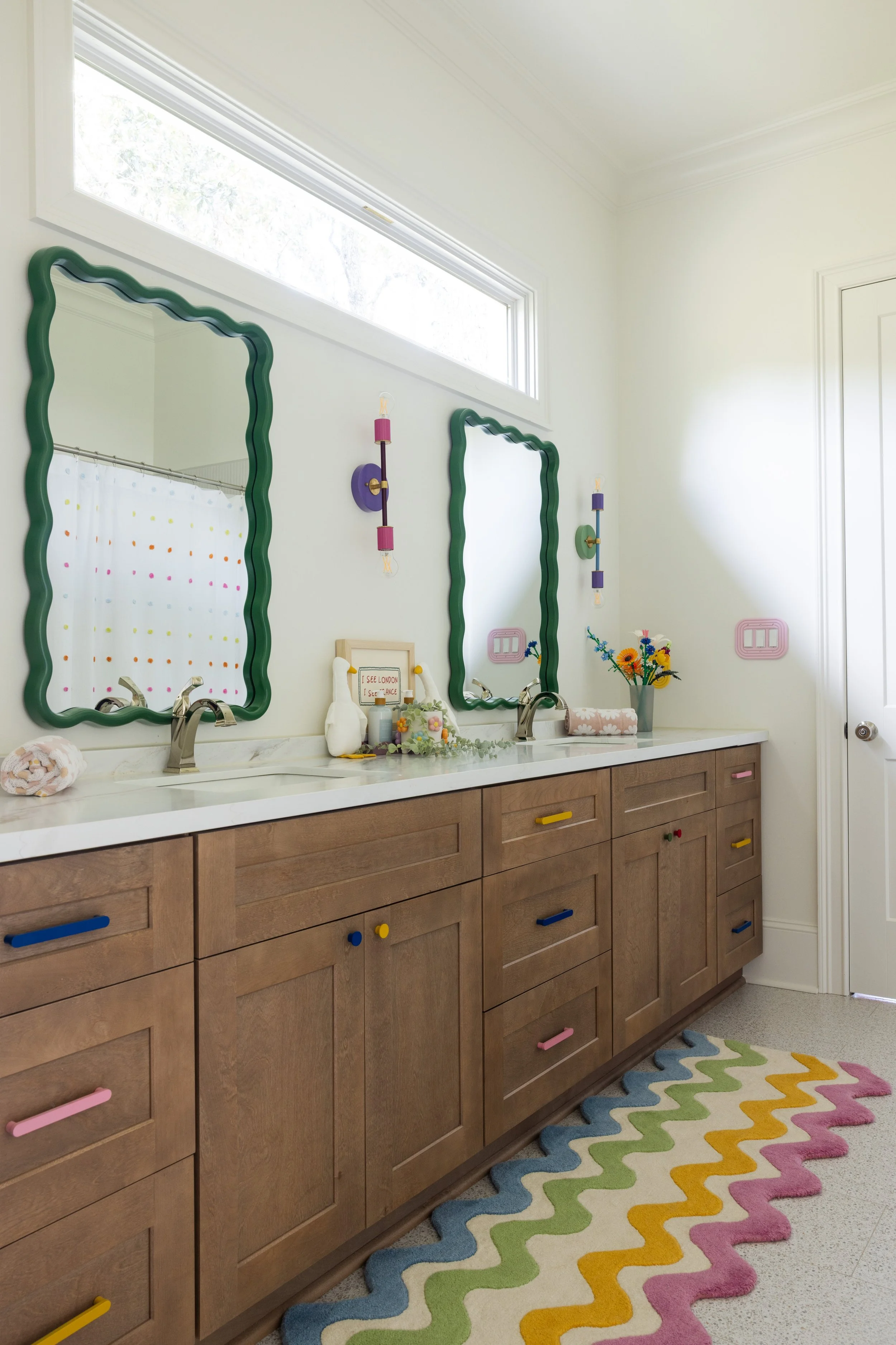 Kids' double vanity with wavy green mirrors and colorful drawer pulls