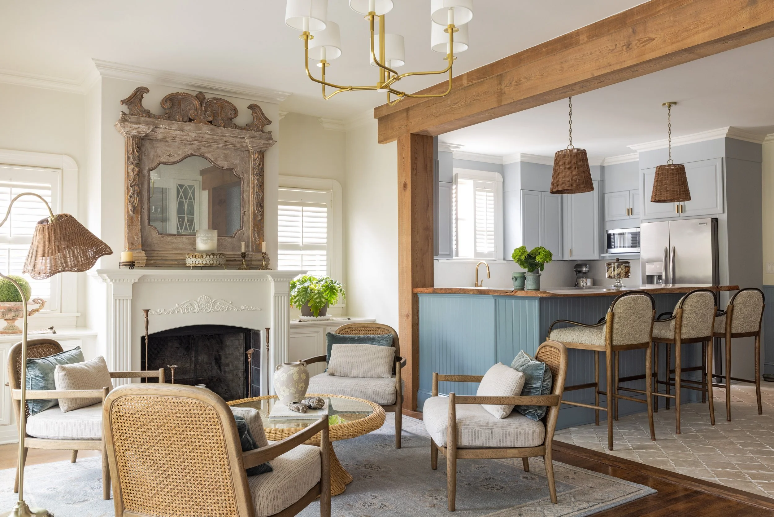 Den opened to the kitchen with a wood beam, brass chandelier, and wicker pendants