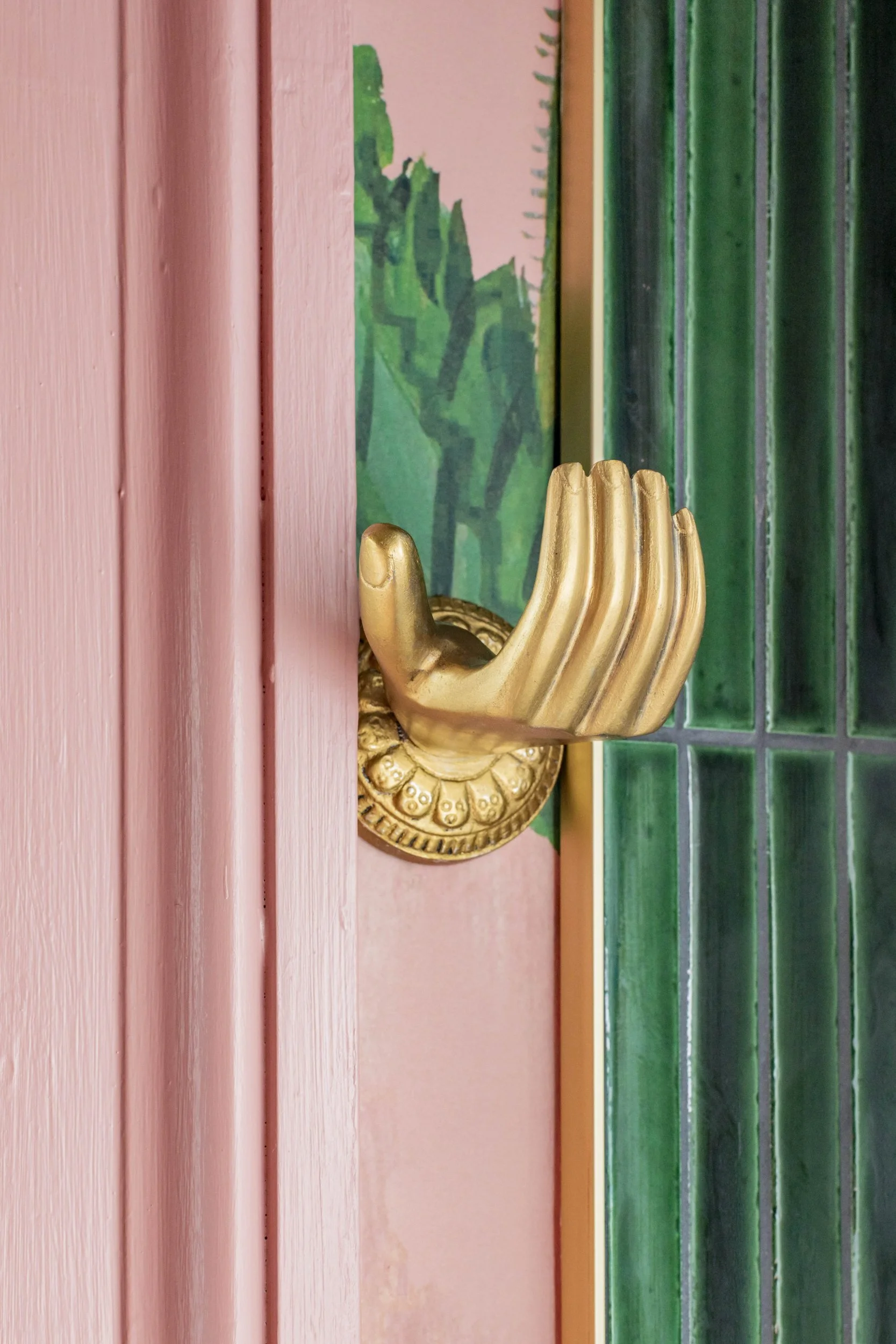 Brass hand towel hook beside green tile