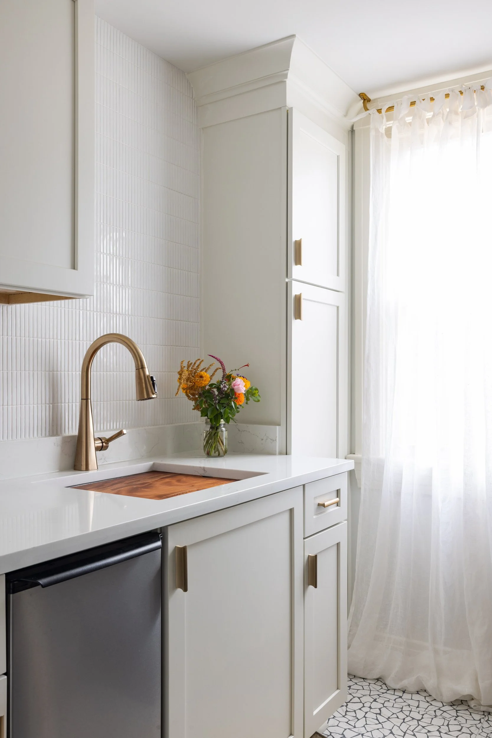 Updated laundry room with cream cabinets, white stick tile, and sheer linen curtain
