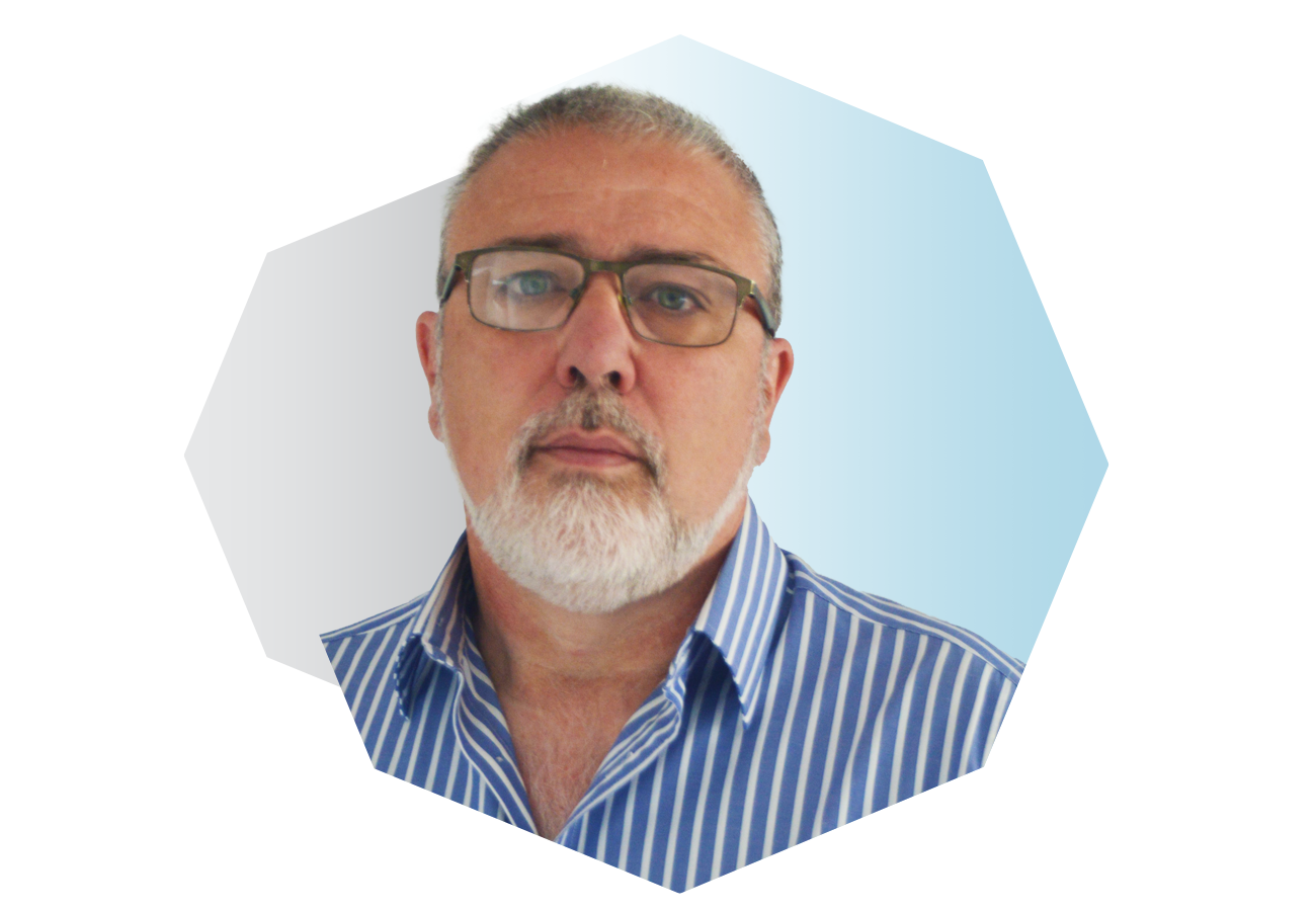 A middle-aged man with glasses, a white beard, and short gray hair, wearing a blue and white striped shirt, looking directly at the camera.