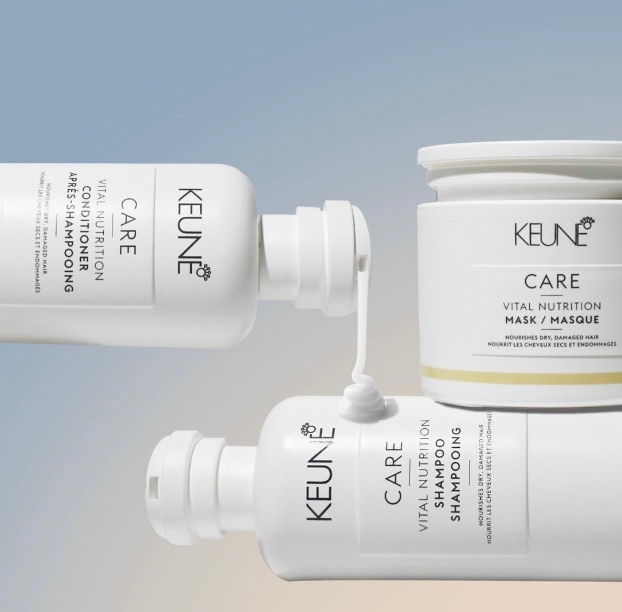 Trois produits capillaires de la marque KEUNE, un shampoing, un masque et un spray, disposés sur un fond dégradé de beige à gris. Le shampoing est en train d'être versé, avec une goutte en suspension.