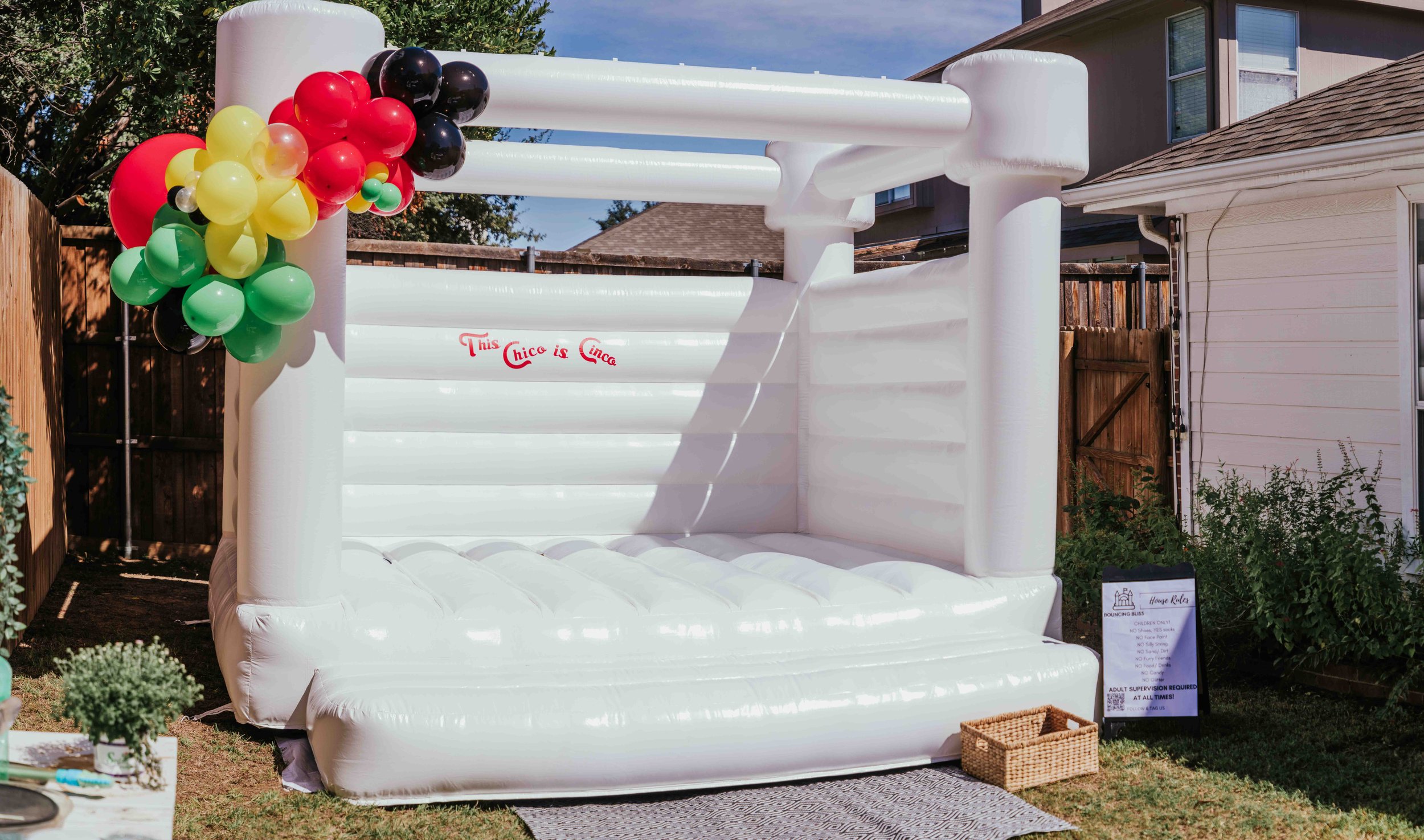White bounce house with a balloon arch.