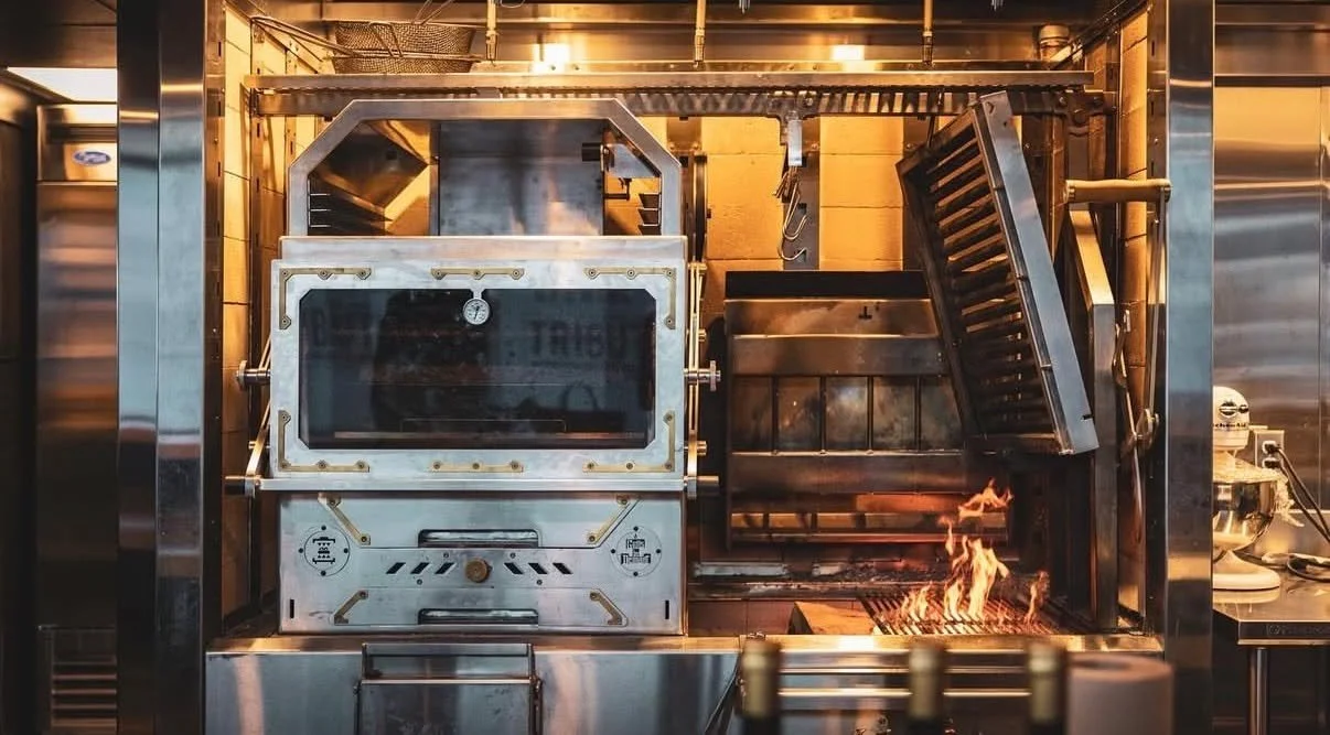 @tribute.restaurant , Halifax, Canada
At the center of the kitchen, fire sets the rhythm.
Tribute&rsquo;s open hearth anchors the space, not as decoration, but as a working tool built for precision, consistency, and restraint.
Here, guests don&rsquo;