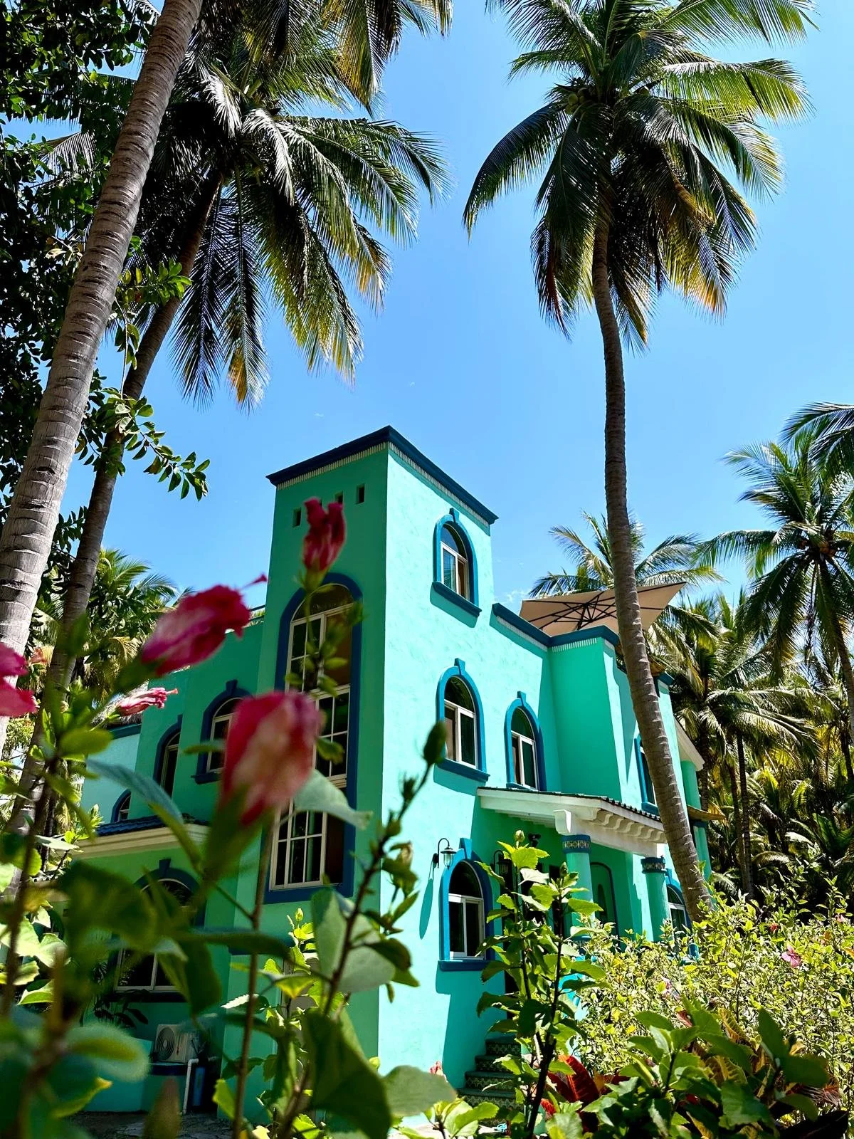 A bright green villa with flower in front.