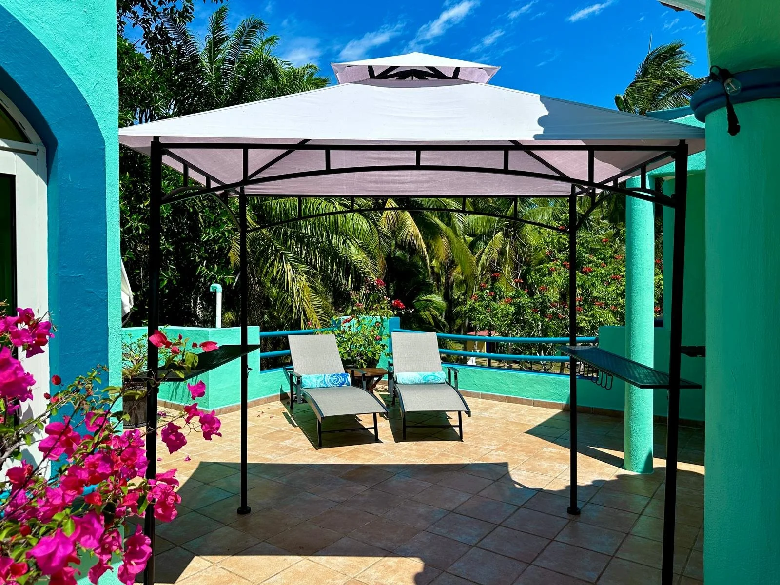 A shade tent on a rooftop deck with two lounge chairs.