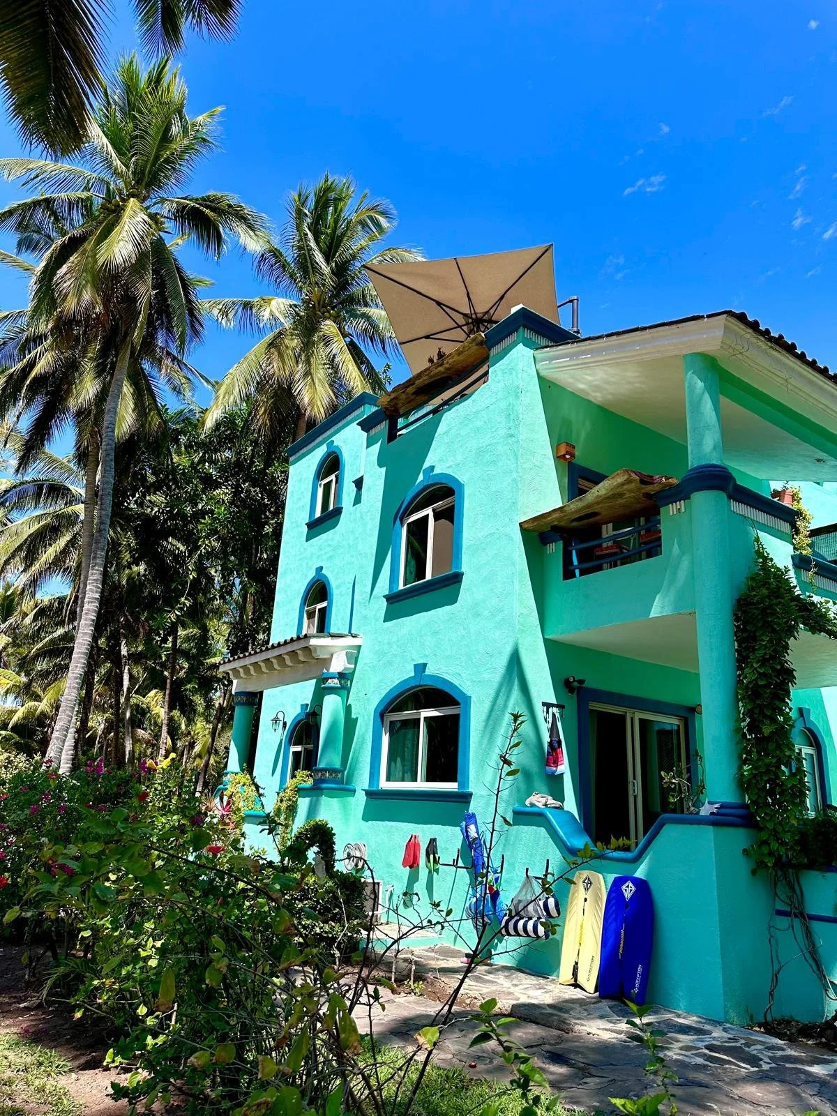 A bright green villa surrounded by tall coconut trees.