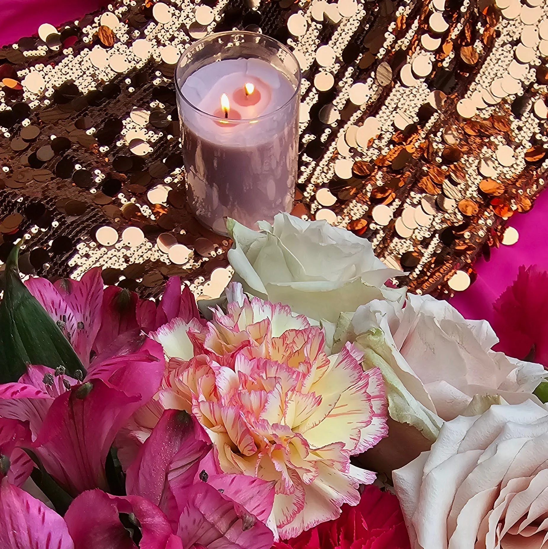 bright flowers next to candle on sequin