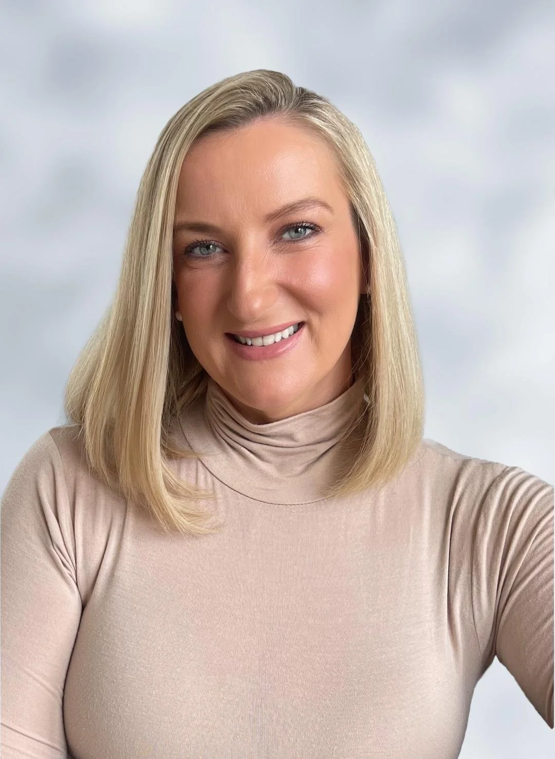 A headshot photo of Jennifer Laptew Williams, with blonde hair and blue eyes and smiling, wearing a beige turtleneck who specializes in anxiety therapy CT