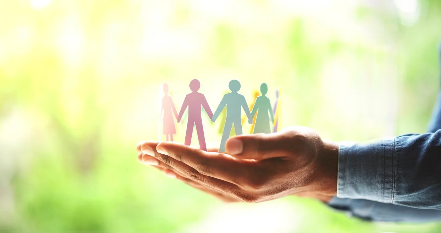 cupped hands gently hold some paper cutout people
