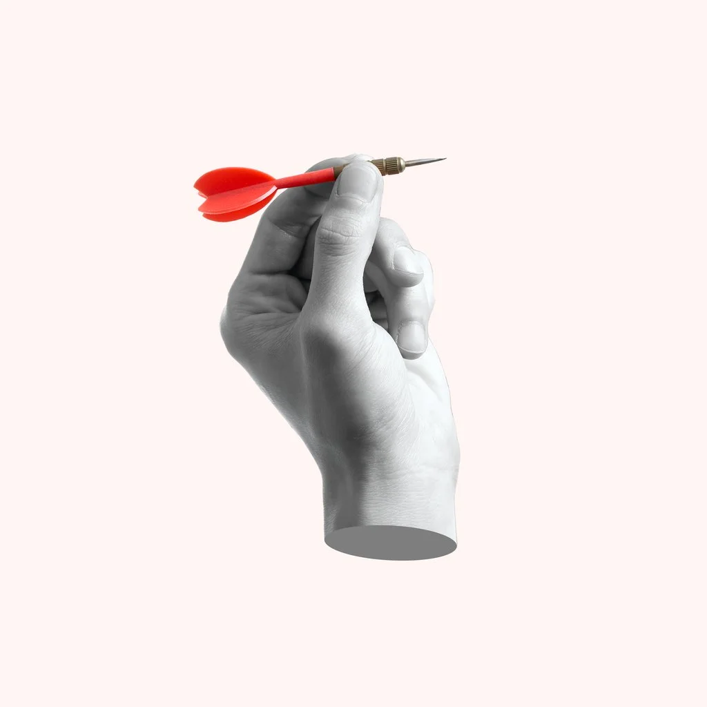 a left hand holding a red dart ready to throw it