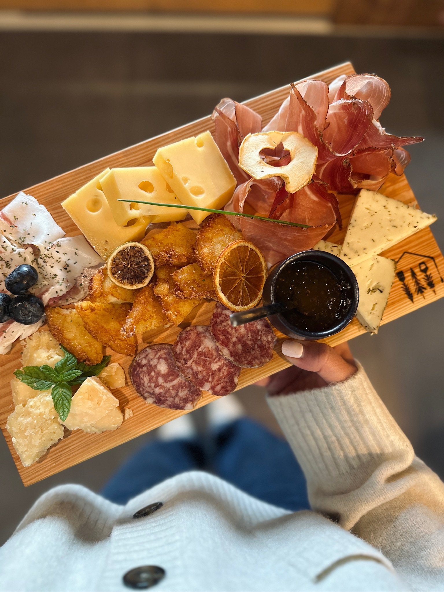 Tagliere di formaggi, salumi e mostarda su un tagliere di legno.