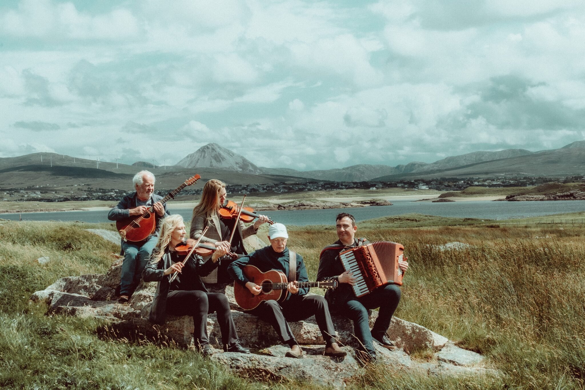 Photo of members of the band Altan plaing traditioanl irish instruments with Mount Errigal Donegal in the backgound