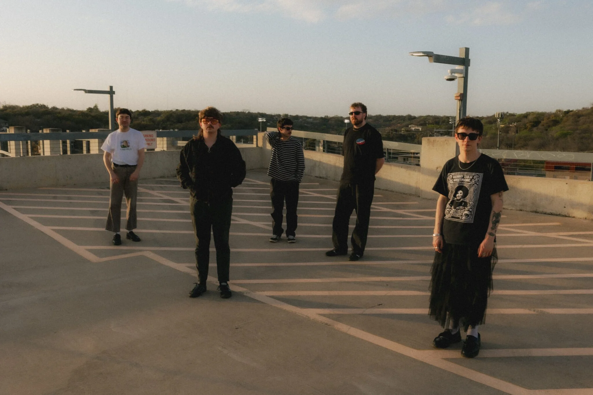 Band Photo , musicians stand on top of a multistory building , very industrial feel, band members look eclectic in their style and poses.