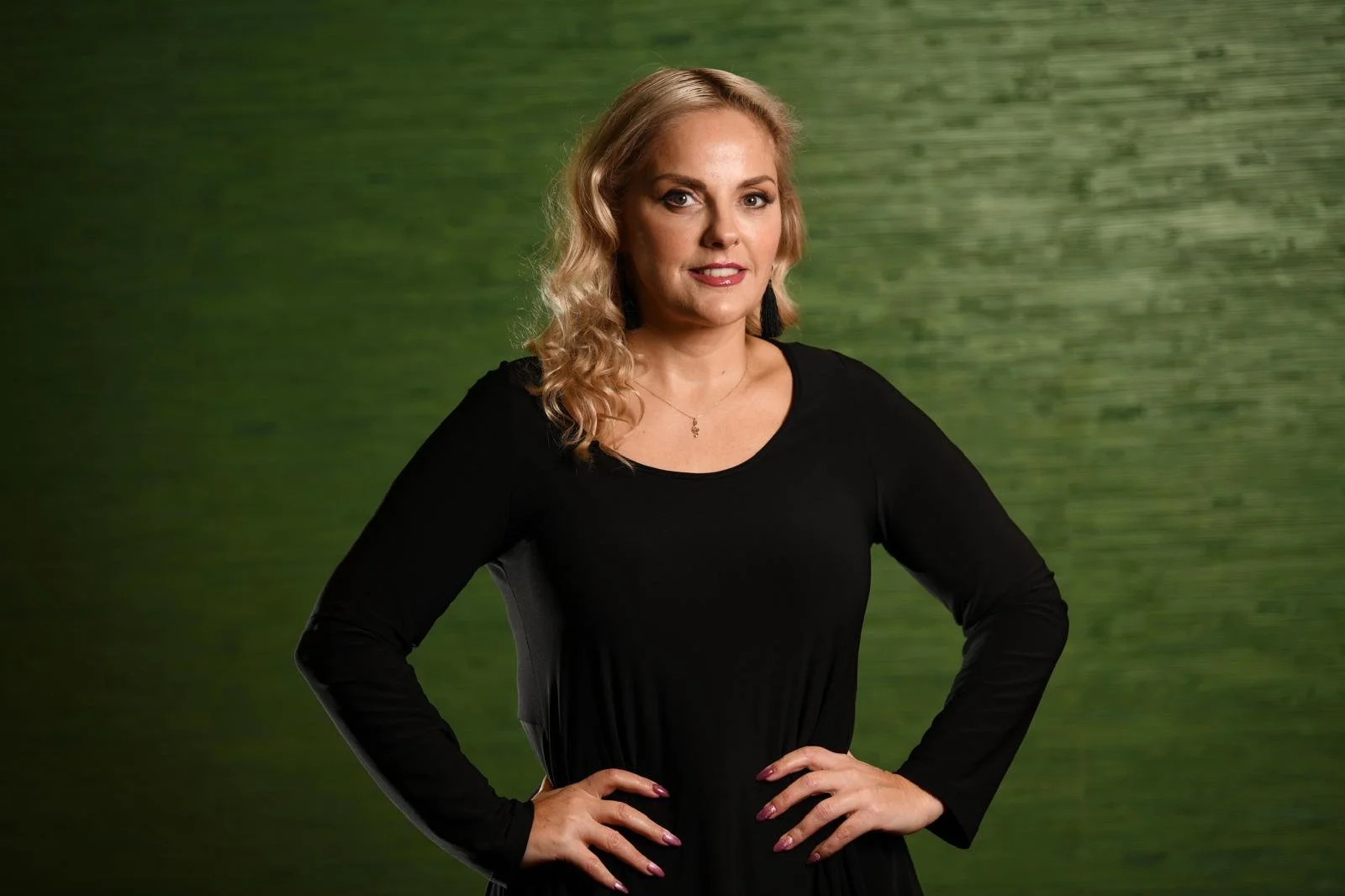 Photo of Celine Byrne wearing black smiling , in a green background