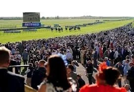 photo of curragh racecourse, image from the stands with punters watching horses and riders approach finish line