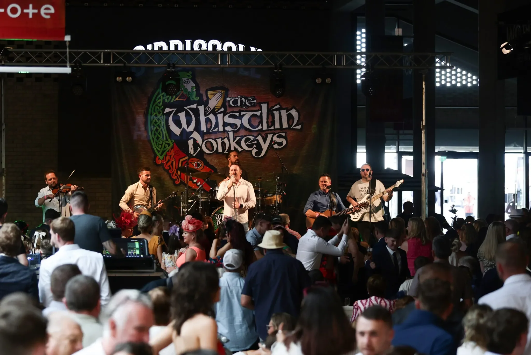 six male band members withh varius musical instruments with banner in background with the band name The Whistlin Donkeys