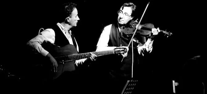 Black and White photo Mazurka  one plays guitar the other violin