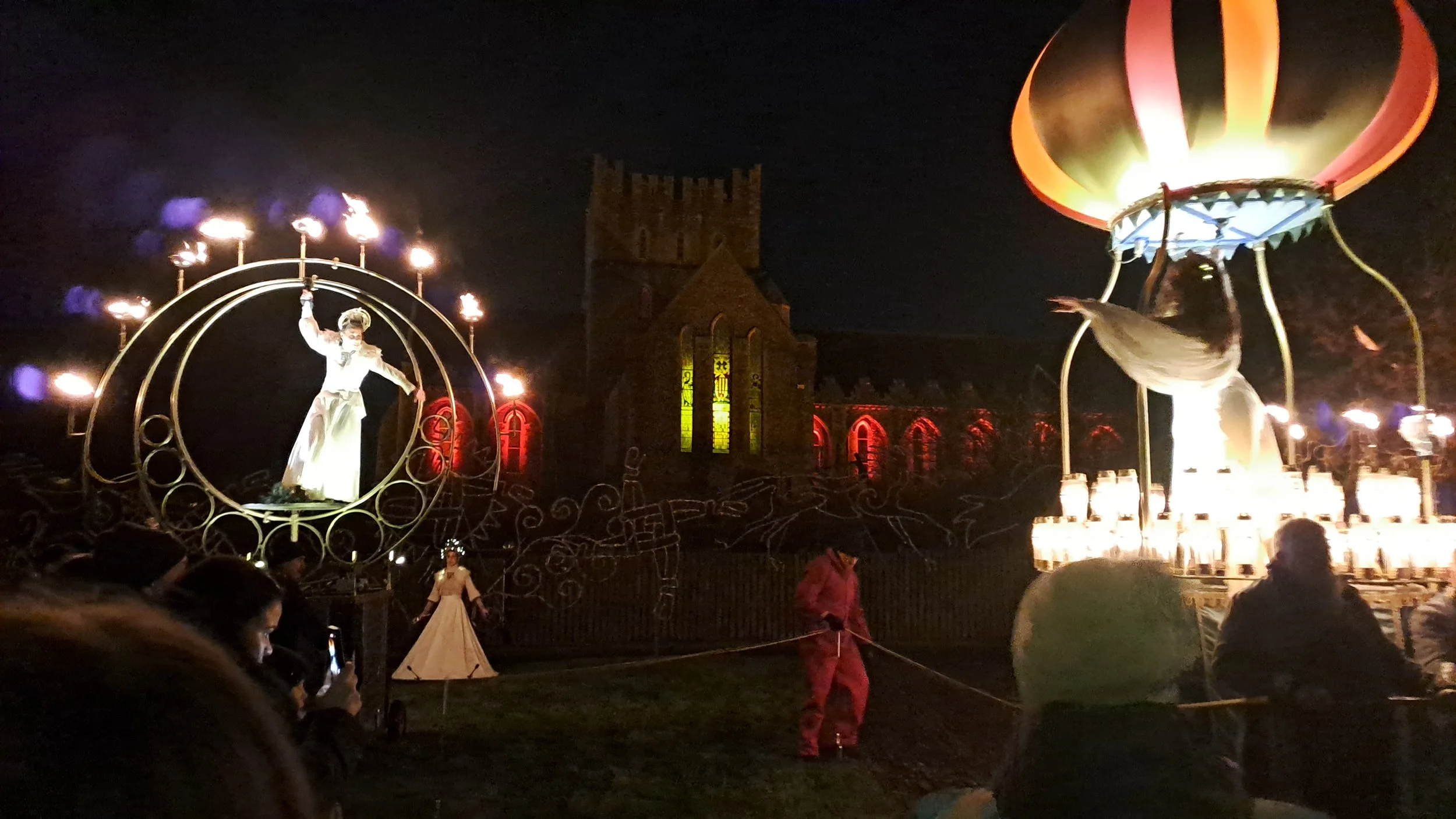 Photo of fire dancers and performers at previous Festival of Light , St Brigids Cathedral is lit up behind, warm tones of red and orange.
