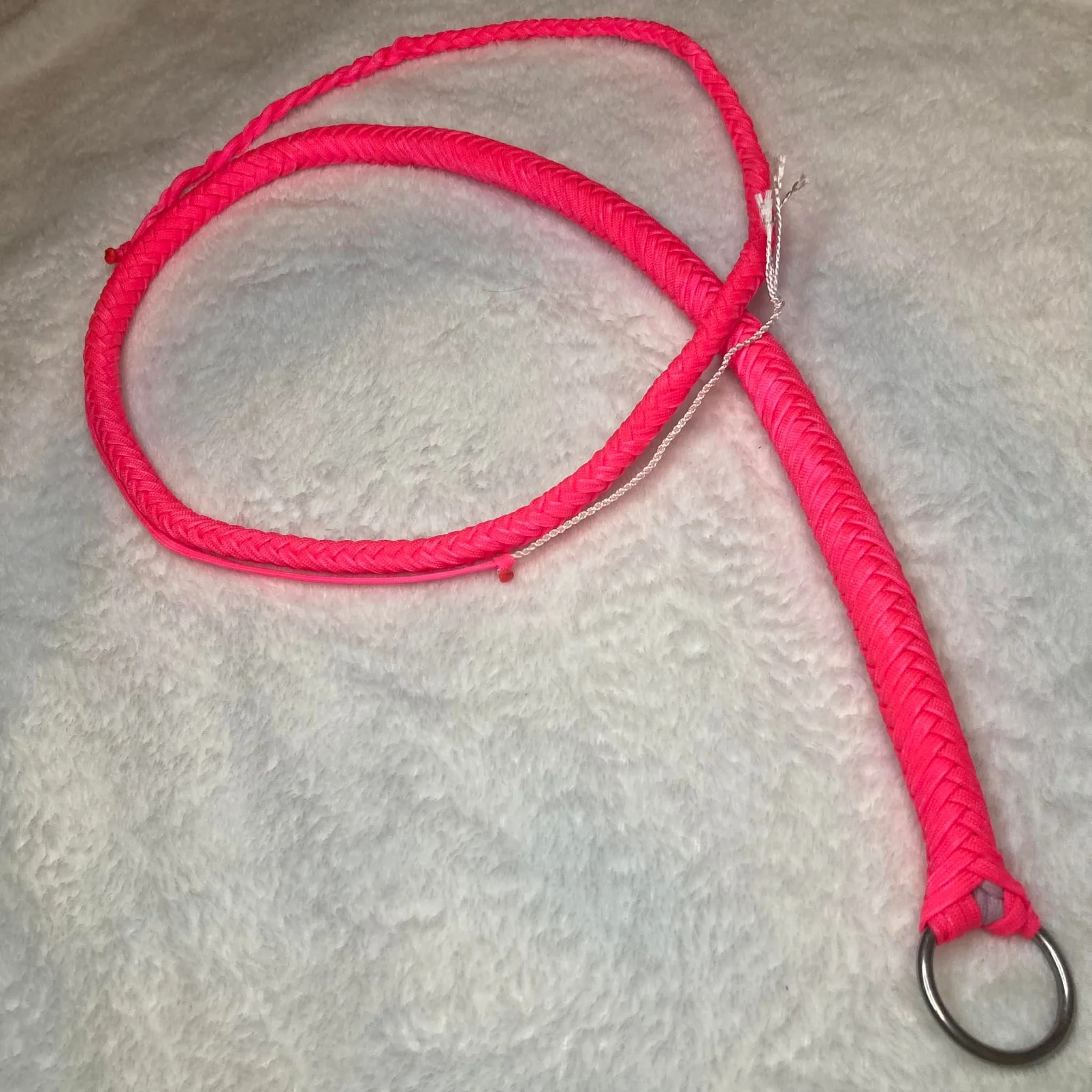 Pink braided leash with metal ring on a soft, light-colored surface.