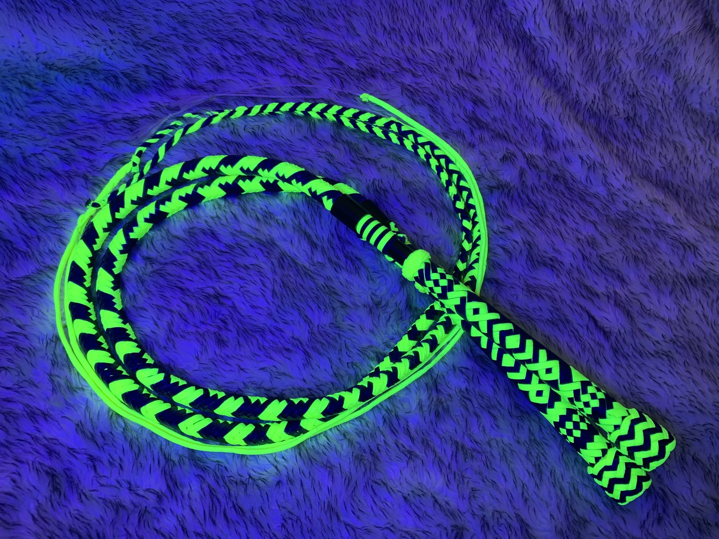Glow-in-the-dark woven leash and handle on a fuzzy surface.