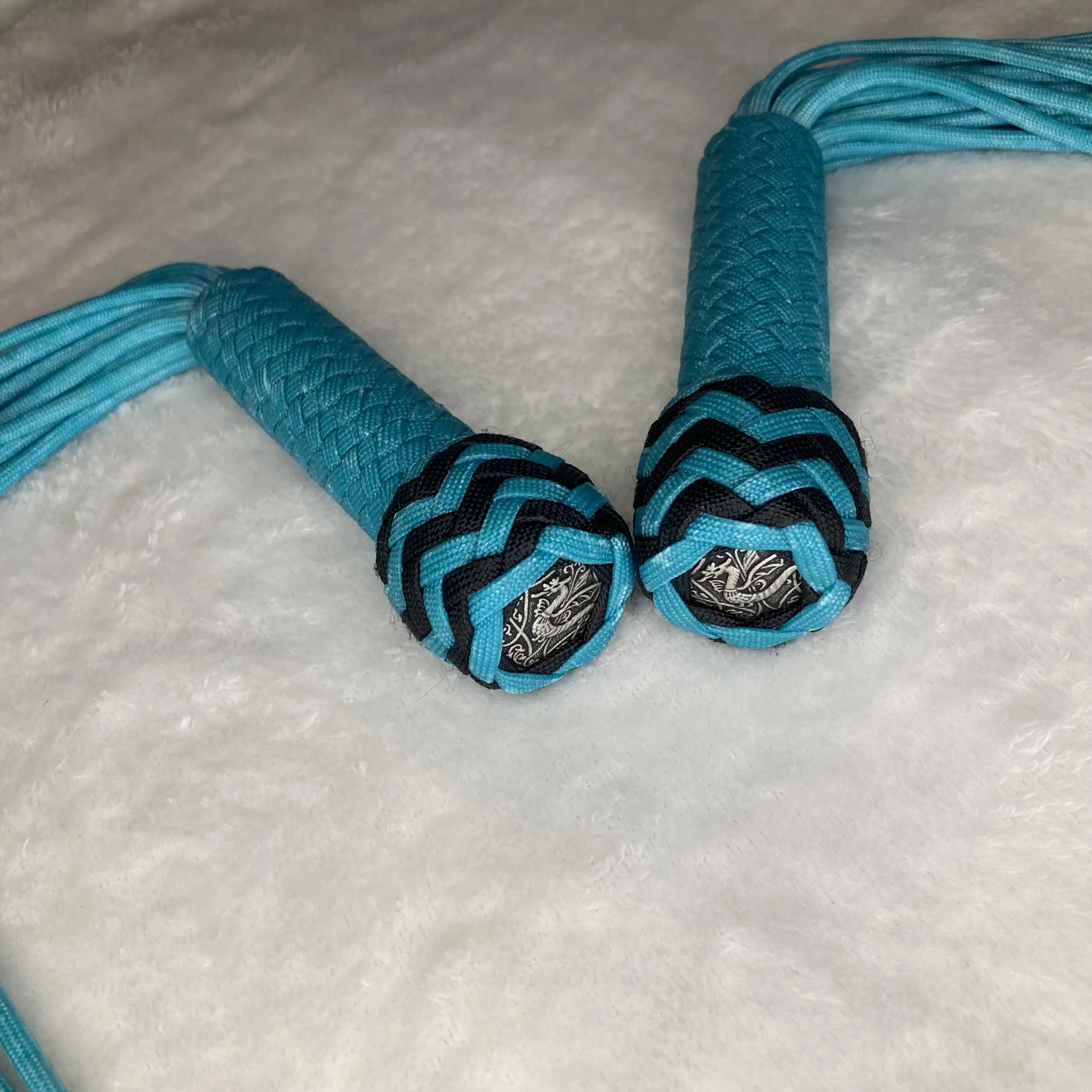 Close-up of a jump rope with blue and black handles resting on a soft white surface.