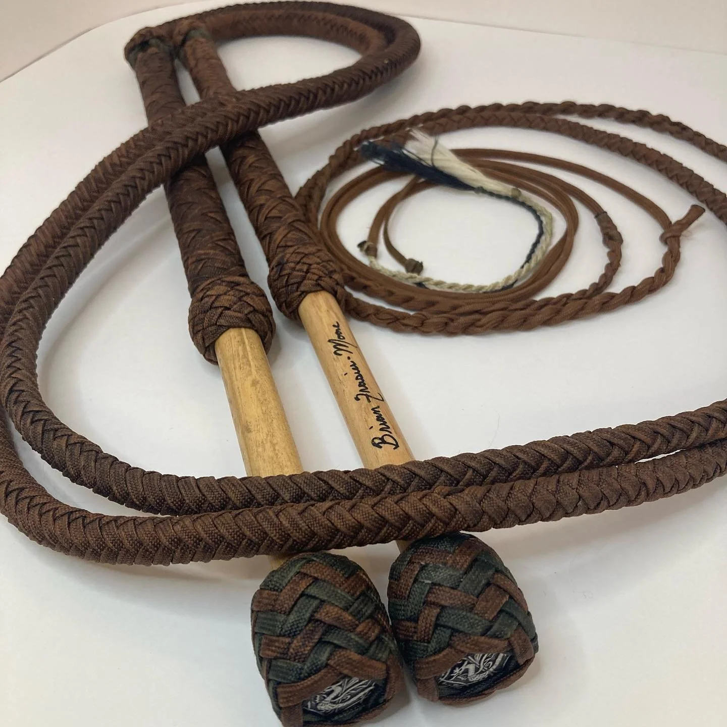 Decorative braided jump ropes with wooden handles and woven fabric-covered ends, placed on a white surface.