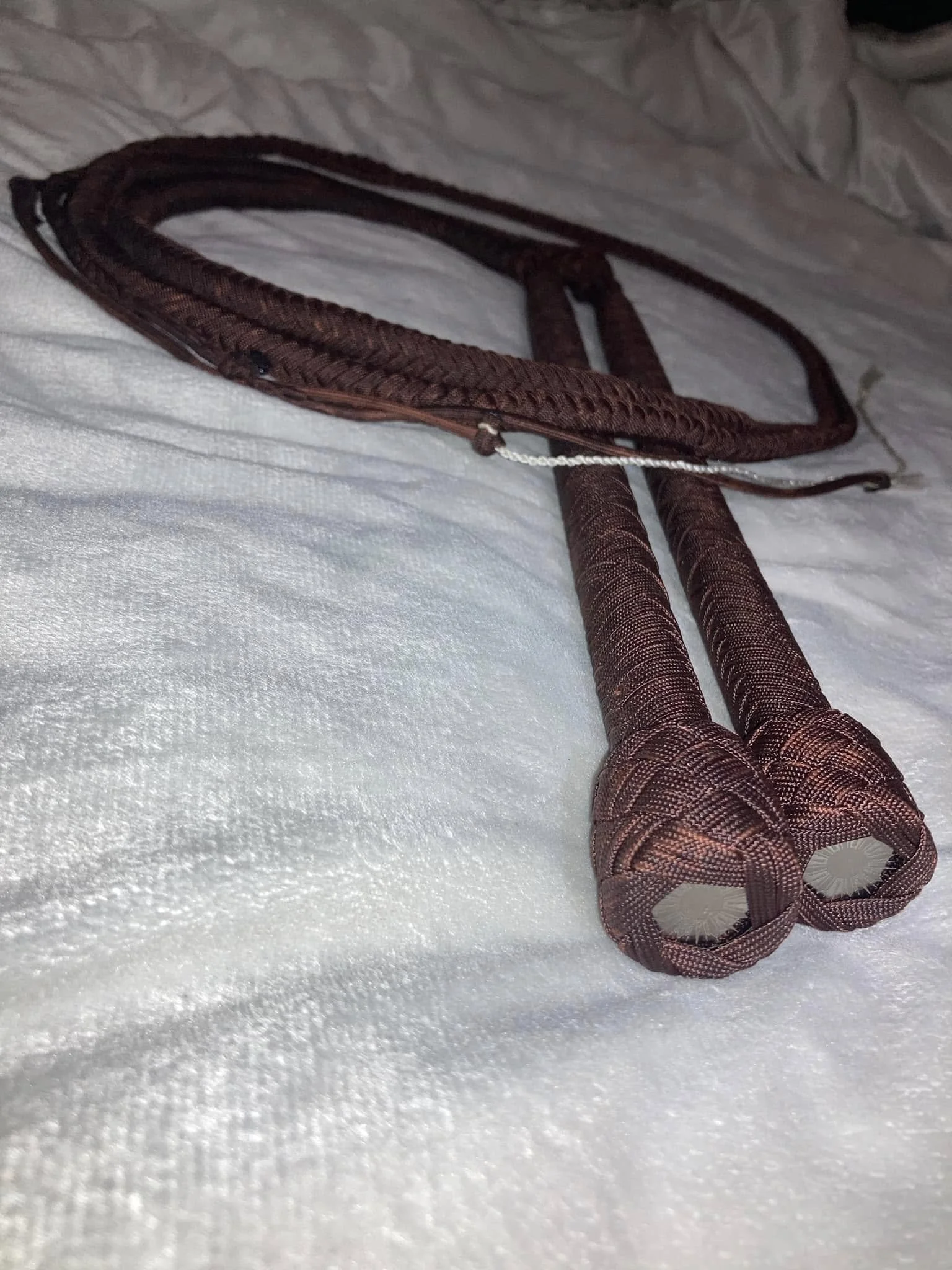A close-up of a jump rope with braided handles resting on a white fabric surface.