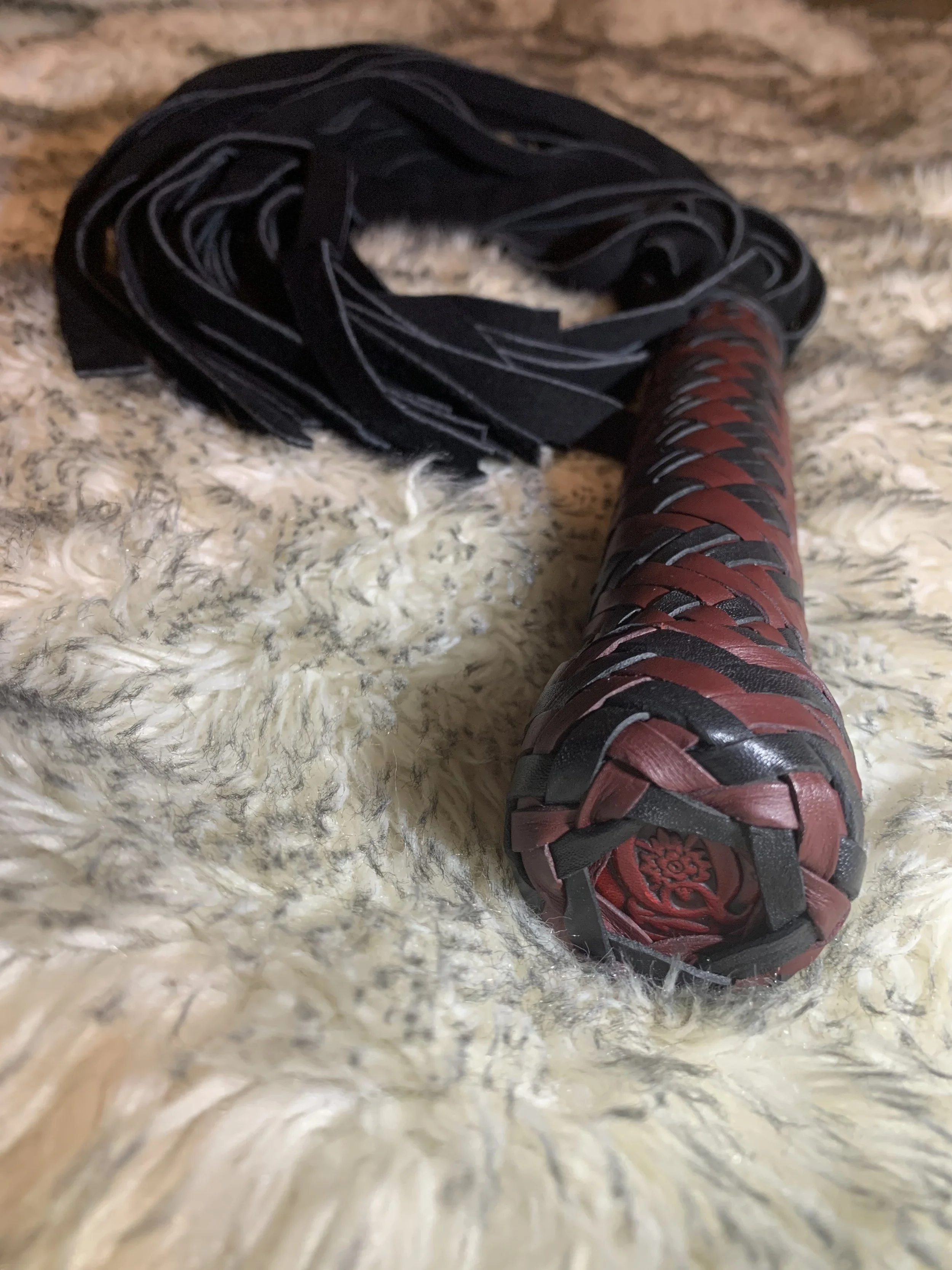 A close-up of a padded black and red flogger.