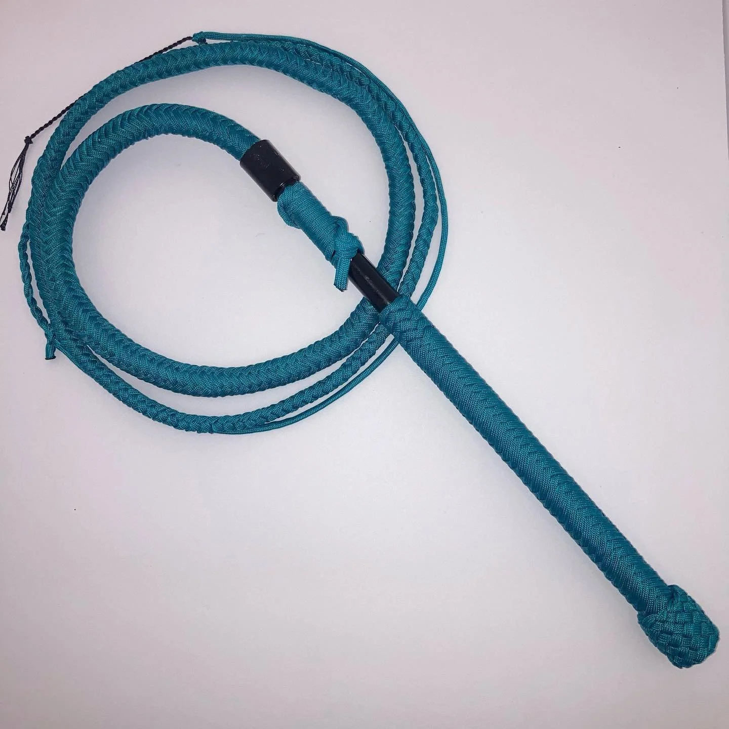 A blue braided whip or riding crop with a handle, on a white surface.