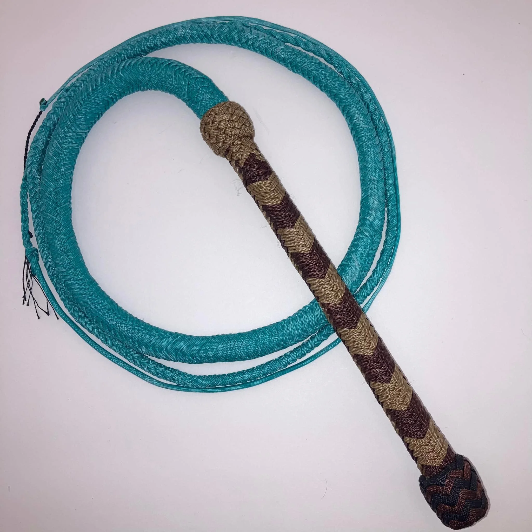 A photograph of a blue jump rope coiled on a white surface with a braided handle resting on top.