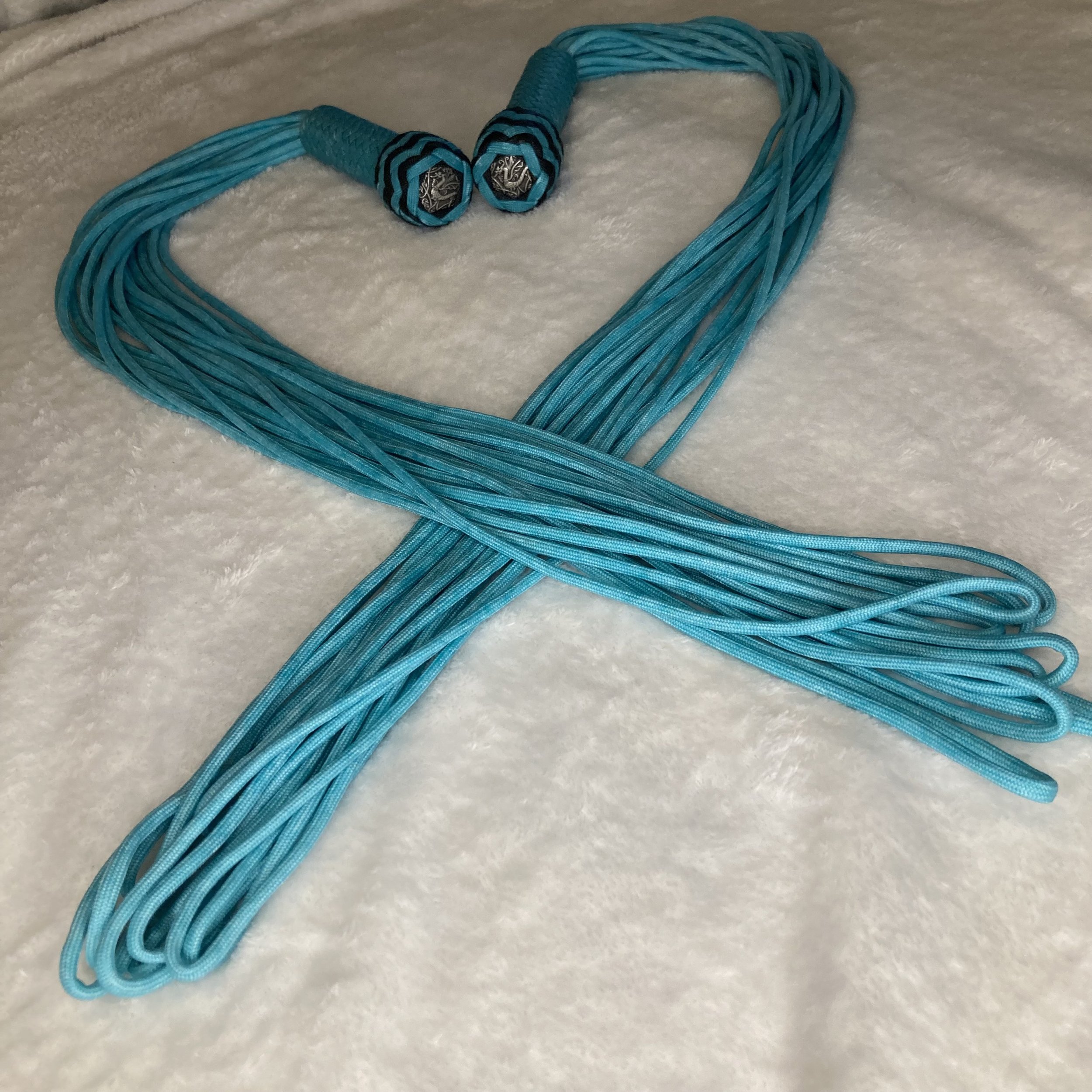 A blue multi-strand necklace with two silver decorative end caps, laid out on a white textured surface.