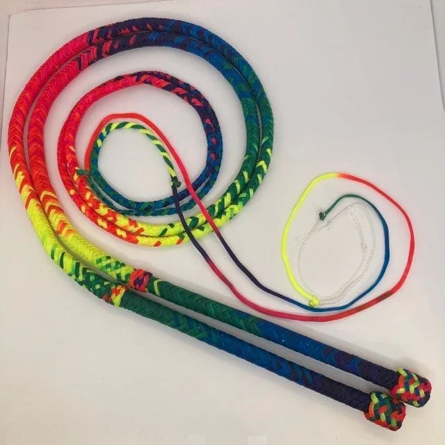 Colorful jump ropes with braided handles, laying on a white surface.