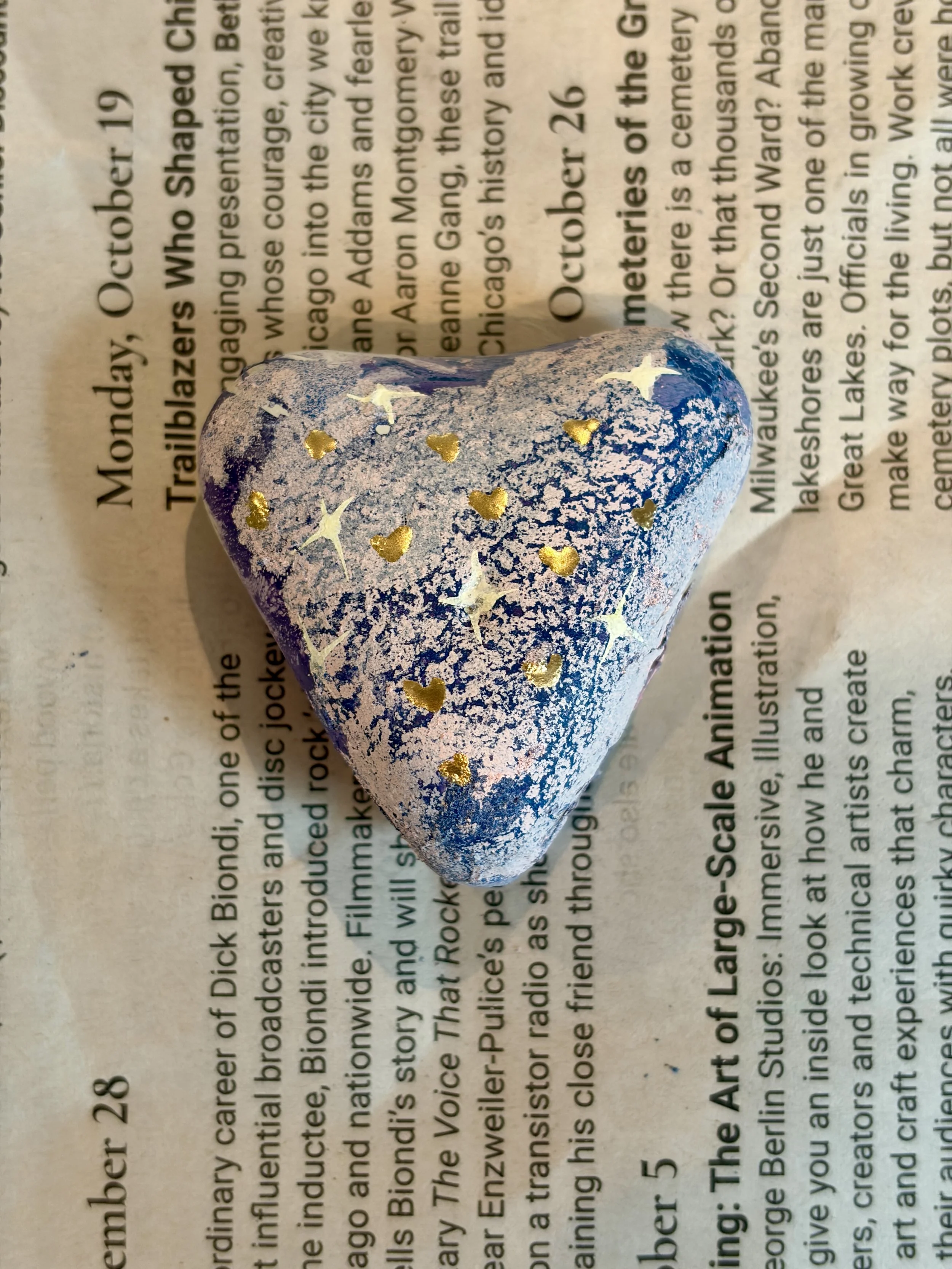 Heart-shaped hydro dipped rock decorated with gold stars and hearts using paint pens