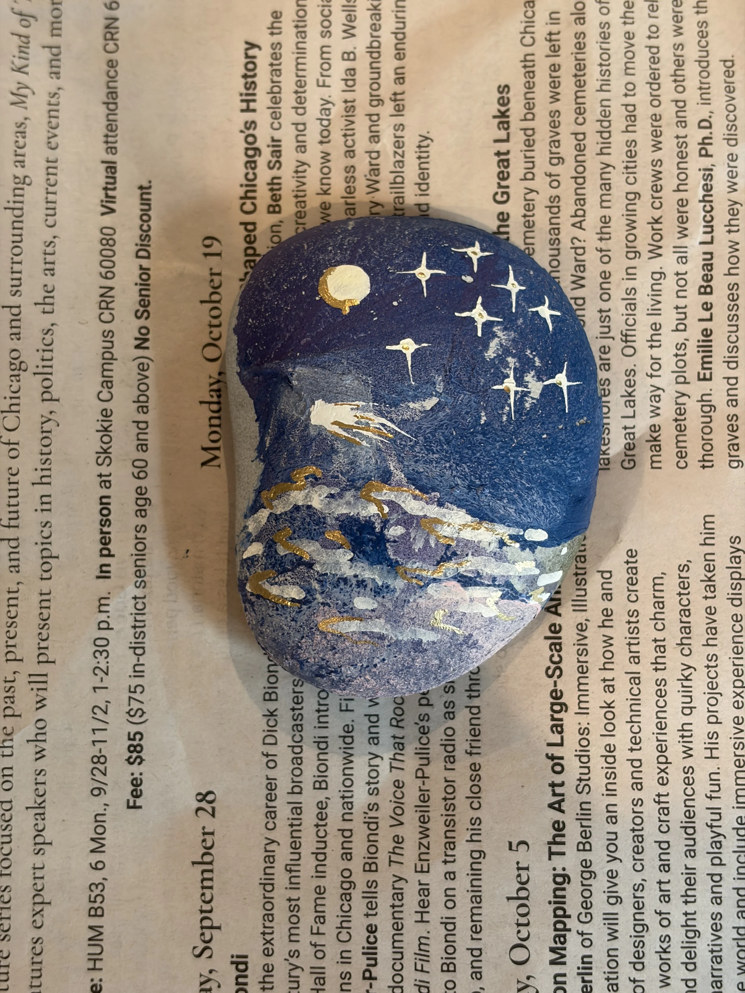 Hydro dipped rock decorated with a gold moon, stars, and mountain design using paint pens